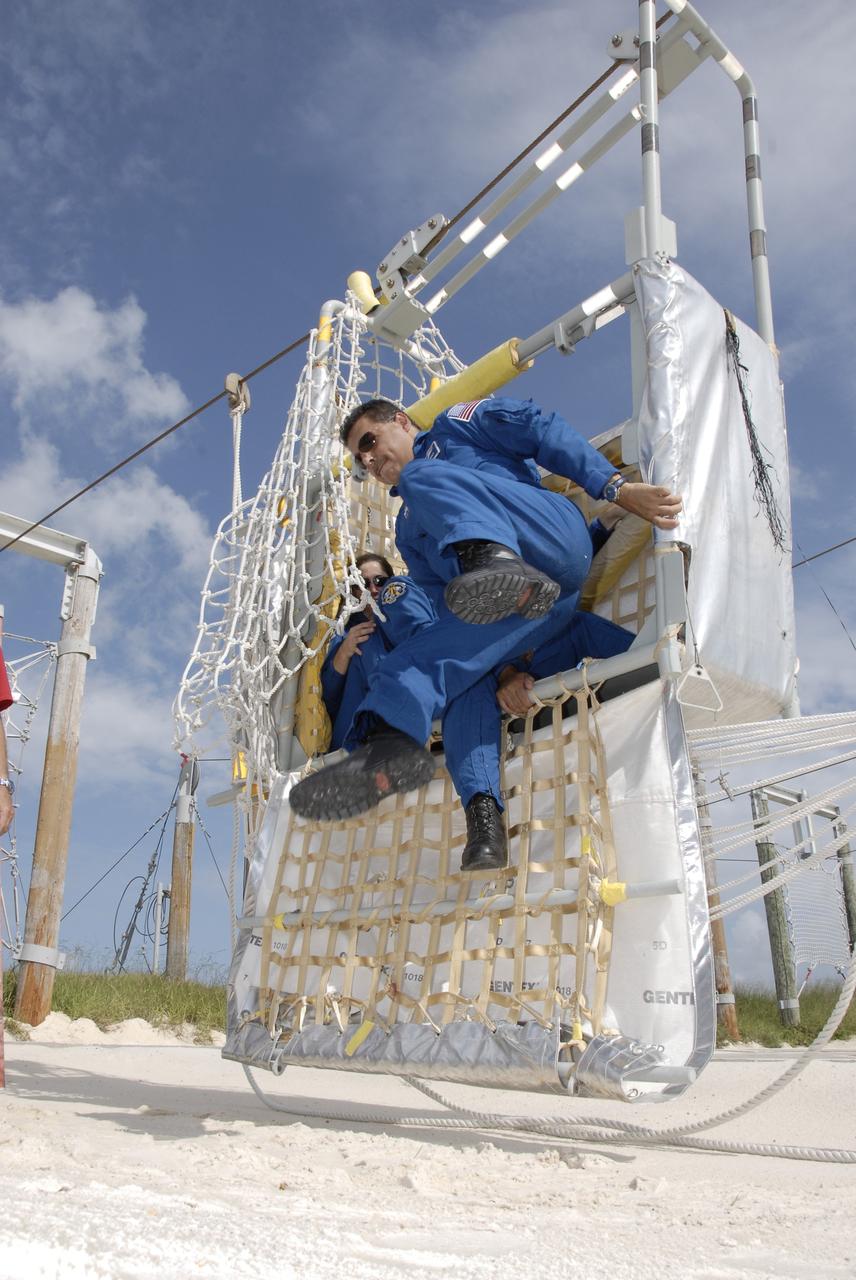 CAPE CANAVERAL, Fla. – At NASA's Kennedy Space Center in Florida, STS-128 Mission Specialist Jose Hernandez practices getting out of a slidewire basket that can be used for emergency exit from Launch Pad 39A.  Still in the basket, at left, is Mission Specialist Nicole Stott.  The crew is at Kennedy for a launch dress rehearsal called the terminal countdown demonstration test, or TCDT, which includes emergency exit training and equipment familiarization, as well as a simulated launch countdown.  Discovery will deliver 33,000 pounds of equipment to the station, including science and storage racks, a freezer to store research samples, a new sleeping compartment and the COLBERT treadmill. Photo credit: NASA/Kim Shiflett