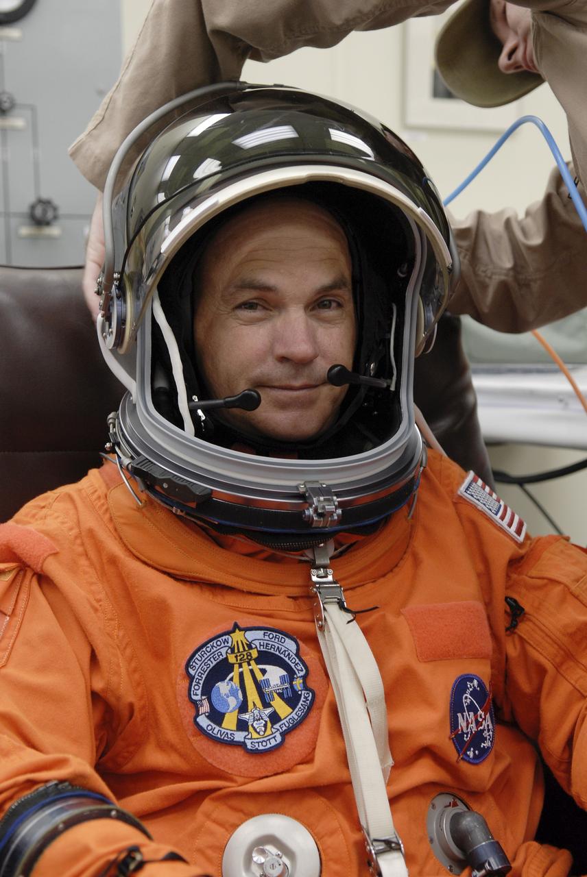 CAPE CANAVERAL, Fla. – A worker helps secure the helmet on STS-128 Commander Rick Sturckow as he checks the fit before heading to the NASA Kennedy Space Center's Launch Pad 39A for the simulated launch countdown. The countdown is the culmination of terminal countdown demonstration test activities to prepare the STS-128 crew for launch on space shuttle Discovery's STS-128 mission. Discovery will deliver 33,000 pounds of equipment to the station, including science and storage racks, a freezer to store research samples, a new sleeping compartment and the COLBERT treadmill. Launch is targeted for late August. Photo credit: NASA/Kim Shiflett