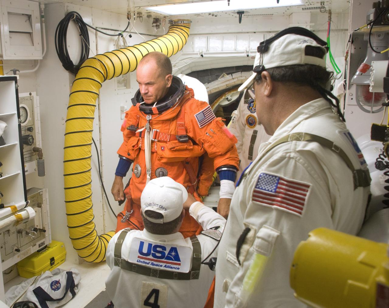 CAPE CANAVERAL, Fla. – In the White Room on NASA Kennedy Space Center's Launch Pad 39A, STS-128 Commander Rick Sturckow is helped with his harness before entering space shuttle Discovery. The White Room is at the end of the orbiter access arm and provides entry into the shuttle. The crew is at Kennedy to take part in the terminal countdown demonstration test, or TCDT, which includes equipment familiarization, emergency exit training and a simulated countdown. On the STS-128 mission, Discovery will deliver 33,000 pounds of equipment to the station, including science and storage racks, a freezer to store research samples, a new sleeping compartment and the COLBERT treadmill.  Launch is targeted for late August.  Photo credit: NASA/Kim Shiflett