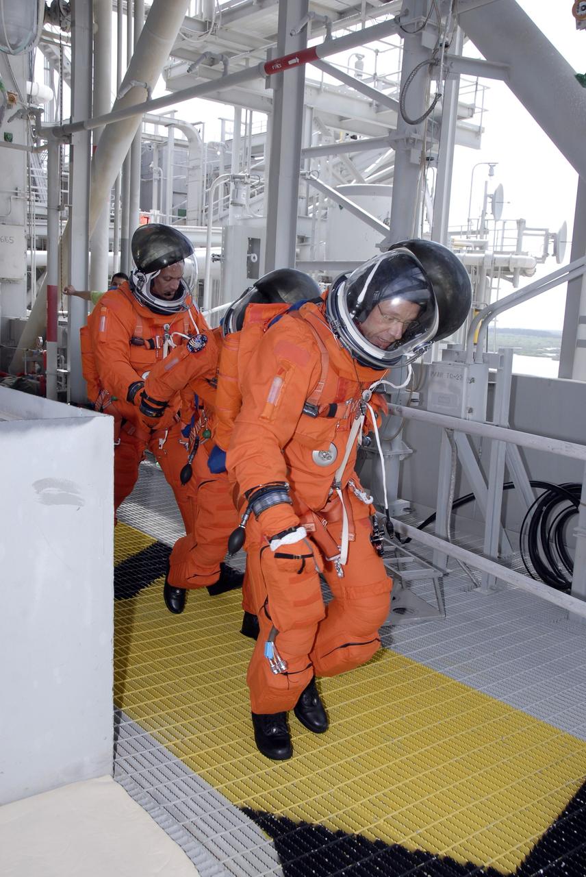CAPE CANAVERAL, Fla. – After a successful simulated launch countdown, STS-128 Mission Specialists (from left) Danny Olivas, Nicole Stott and Christer Fuglesang hurry to the slidewire basket area on NASA Kennedy Space Center's fixed service structure. They are practicing emergency exit from the pad. They and other mission crew members are at Kennedy to take part in the terminal countdown demonstration test, or TCDT, which includes emergency exit training and culminates in the simulated countdown. On the STS-128 mission, Discovery will deliver 33,000 pounds of equipment to the station, including science and storage racks, a freezer to store research samples, a new sleeping compartment and the COLBERT treadmill. Launch is targeted for late August. Photo credit: NASA/Kim Shiflett