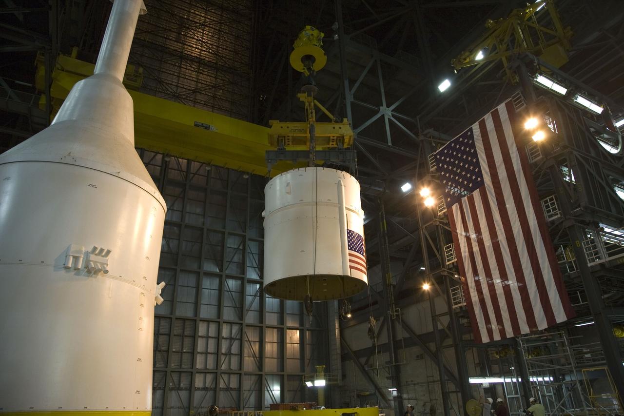CAPE CANAVERAL, Fla. – In the Vehicle Assembly Building's High Bay 4 at NASA's Kennedy Space Center in Florida, a crane lifts the Ares I-X Super Stack 4.  The stack will be moved to High Bay 3 for integration with Super Stack 3. At left is the crew module-launch abort system and simulator service module-service adapter stack.   Five super stacks make up the upper stage that will be integrated with the four-segment solid rocket booster first stage on the mobile launch platform.  Ares I-X is the test vehicle for the Ares I, which is part of the Constellation Program to return men to the moon and beyond. The Ares I-X flight test is targeted for  Oct. 31, pending formal NASA Headquarters approval. Photo credit: NASA/Dimitri Gerondidakis