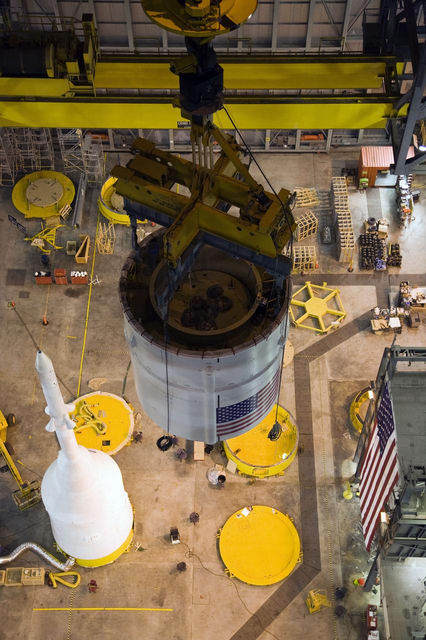 CAPE CANAVERAL, Fla. – In the Vehicle Assembly Building's High Bay 4 at NASA's Kennedy Space Center in Florida, a crane moves the Ares I-X Super Stack 4 across the floor to High Bay 3 for integration with Super Stack 3. Below left is the crew module-launch abort system and simulator service module-service adapter stack. Five super stacks make up the upper stage that will be integrated with the four-segment solid rocket booster first stage on the mobile launch platform. Ares I-X is the test vehicle for the Ares I, which is part of the Constellation Program to return men to the moon and beyond. The Ares I-X flight test is targeted for Oct. 31, pending formal NASA Headquarters approval. Photo credit: NASA/Dimitri Gerondidakis