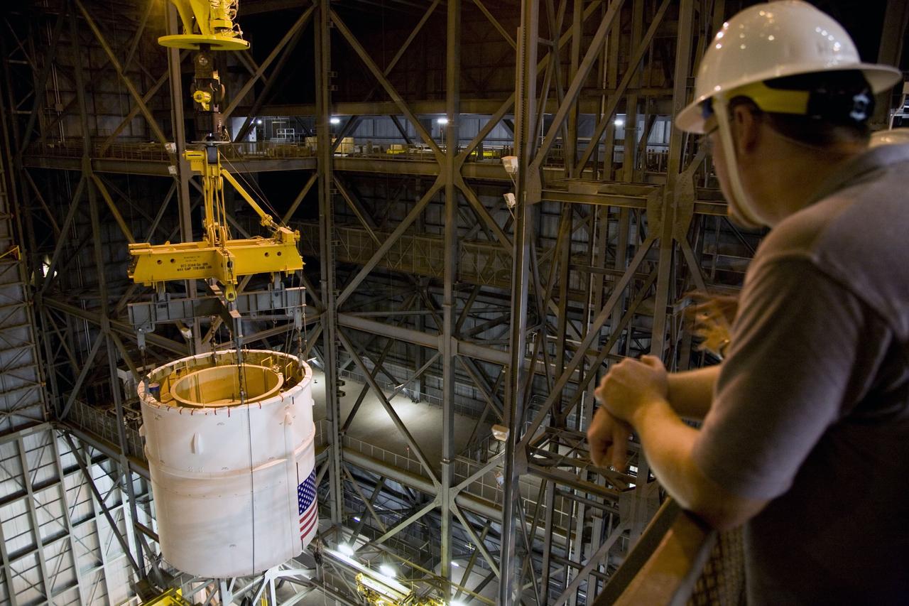 CAPE CANAVERAL, Fla. – In the Vehicle Assembly Building's High Bay 4 at NASA's Kennedy Space Center in Florida, workers at right watch as a crane lifts the Ares I-X Super Stack 4 into the upper levels for transfer to High Bay 3. There it will be integrated with Super Stack 3. Five super stacks make up the upper stage that will be integrated with the four-segment solid rocket booster first stage on the mobile launch platform. Ares I-X is the test vehicle for the Ares I, which is part of the Constellation Program to return men to the moon and beyond. The Ares I-X flight test is targeted for Oct. 31, pending formal NASA Headquarters approval. Photo credit: NASA/Dimitri Gerondidakis