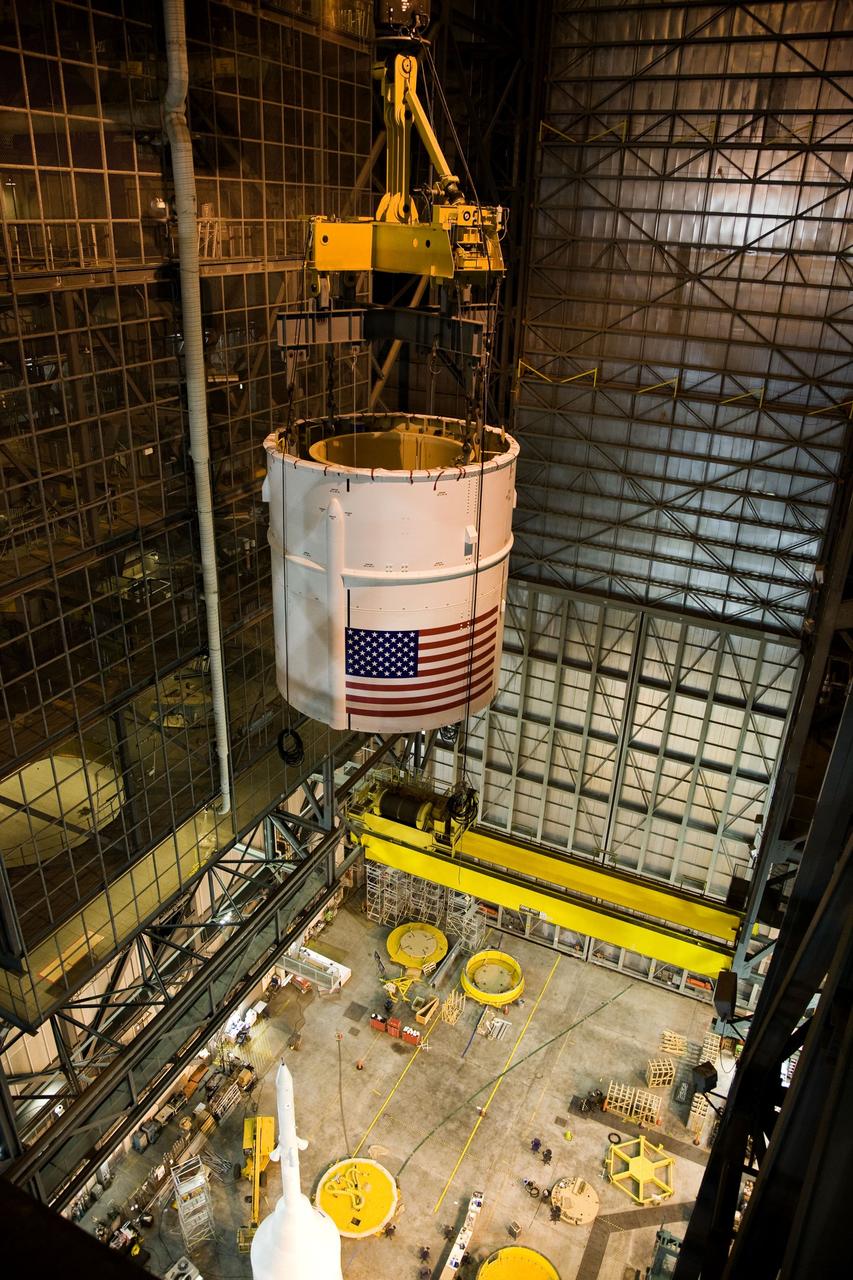 CAPE CANAVERAL, Fla. – In the Vehicle Assembly Building's High Bay 4 at NASA's Kennedy Space Center in Florida, a crane lifts the Ares I-X Super Stack 4 into the upper levels for transfer to High Bay 3 where it will be integrated with Super Stack 3. On the floor below, at left, can be seen the crew module-launch abort system and simulator service module-service adapter stack. Five super stacks make up the upper stage that will be integrated with the four-segment solid rocket booster first stage on the mobile launch platform. Ares I-X is the test vehicle for the Ares I, which is part of the Constellation Program to return men to the moon and beyond. The Ares I-X flight test is targeted for Oct. 31, pending formal NASA Headquarters approval. Photo credit: NASA/Dimitri Gerondidakis