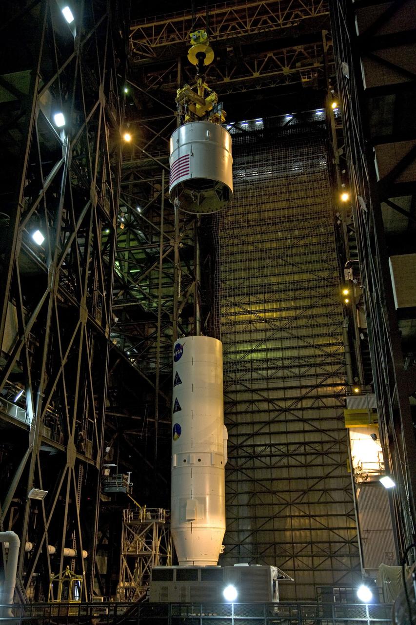 CAPE CANAVERAL, Fla. – In the Vehicle Assembly Building's High Bay 3, a crane lowers the Ares I-X Super Stack 4 toward Super Stack 3 for integration. Five super stacks make up the upper stage that will be integrated with the four-segment solid rocket booster first stage on the mobile launch platform. Ares I-X is the test vehicle for the Ares I, which is part of the Constellation Program to return men to the moon and beyond. The Ares I-X flight test is targeted for Oct. 31, pending formal NASA Headquarters approval. Photo credit: NASA/Dimitri Gerondidakis