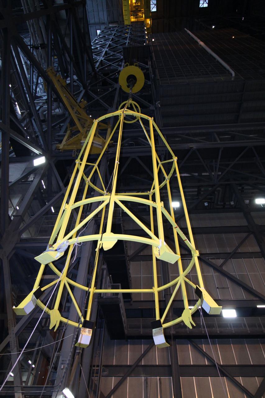 CAPE CANAVERAL, Fla. – In the Vehicle Assembly Building's High Bay 4, assembly of the Ares I-X rocket nears completion. The yellow framework, nicknamed the "birdcage," is lowered by crane toward Super Stack 5. The birdcage has the ability to lift and to stack and de-stack the Ares I-X rocket's Super Stack 5. Next, the stack will be lifted on top of the segments already in place on the mobile launcher platform, completing assembly of the rocket.  Five super stacks make up the rocket's upper stage that will be integrated with the four-segment solid rocket booster first stage. Ares I-X is the test vehicle for the Ares I, which is part of the Constellation Program to return men to the moon and beyond. The Ares I-X flight test is targeted for Oct. 31, pending formal NASA Headquarters approval. Photo credit: NASA/Jack Pfaller