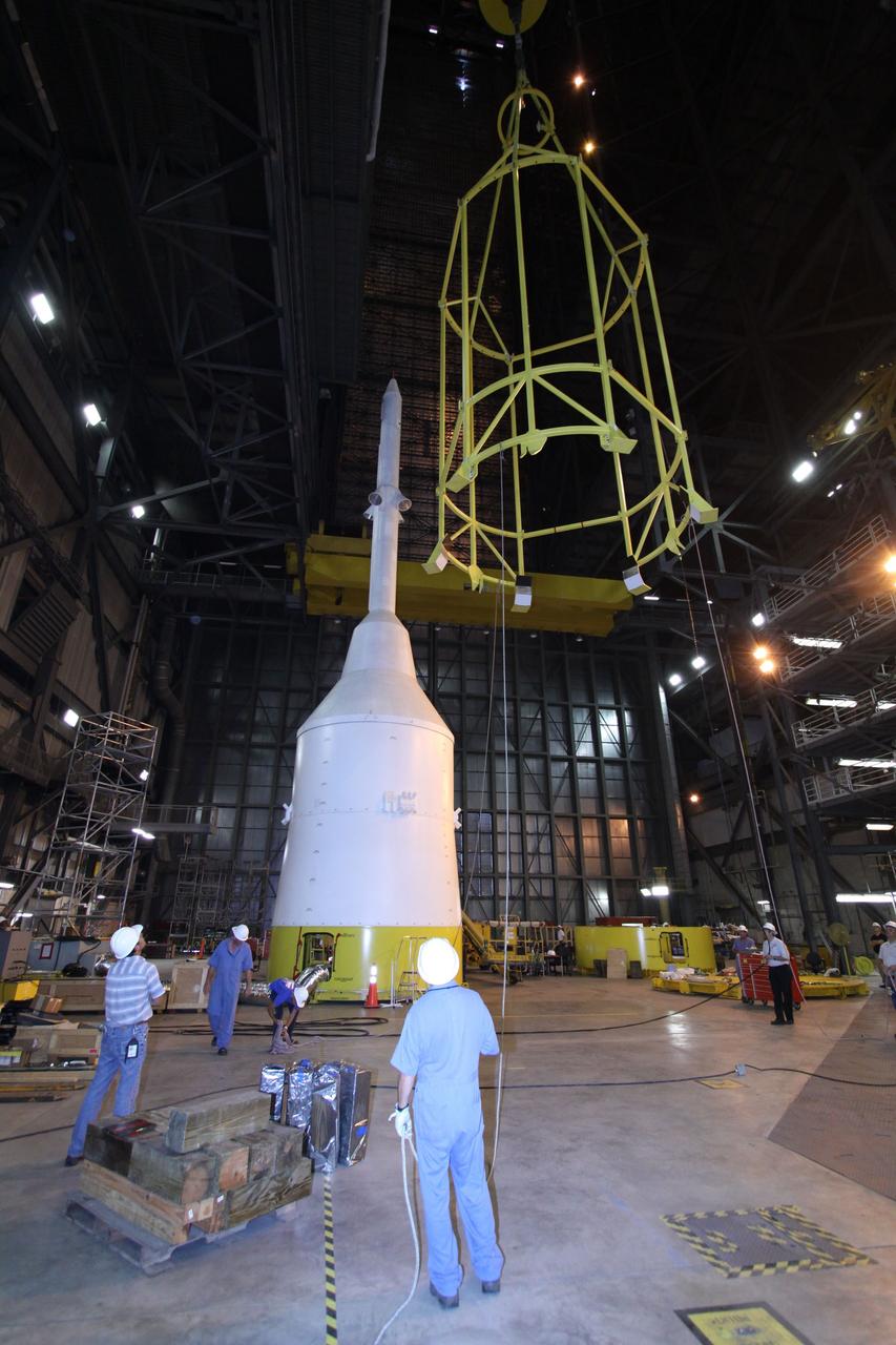 CAPE CANAVERAL, Fla. – In the Vehicle Assembly Building's High Bay 4, assembly of the Ares I-X rocket nears completion. Technicians monitor the yellow framework, nicknamed the "birdcage," as it is lowered by crane toward Super Stack 5.  The birdcage has the ability to lift and to stack and de-stack the Ares I-X rocket's Super Stack 5. Next, the stack will be lifted on top of the segments already in place on the mobile launcher platform, completing assembly of the rocket.  Five super stacks make up the rocket's upper stage that will be integrated with the four-segment solid rocket booster first stage. Ares I-X is the test vehicle for the Ares I, which is part of the Constellation Program to return men to the moon and beyond. The Ares I-X flight test is targeted for Oct. 31, pending formal NASA Headquarters approval. Photo credit: NASA/Jack Pfaller