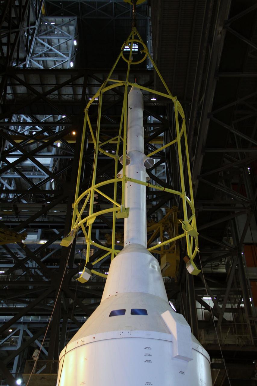 CAPE CANAVERAL, Fla. – In the Vehicle Assembly Building's High Bay 4, assembly of the Ares I-X rocket nears completion. The yellow framework, nicknamed the "birdcage," is lowered by crane over the Launch Abort System, or LAS, of Super Stack 5.  The birdcage has the ability to lift and to stack and de-stack the Ares I-X rocket's Super Stack 5. Next, the stack will be lifted on top of the segments already in place on the mobile launcher platform, completing assembly of the rocket.  Five super stacks make up the rocket's upper stage that will be integrated with the four-segment solid rocket booster first stage. Ares I-X is the test vehicle for the Ares I, which is part of the Constellation Program to return men to the moon and beyond. The Ares I-X flight test is targeted for Oct. 31, pending formal NASA Headquarters approval. Photo credit: NASA/Jack Pfaller