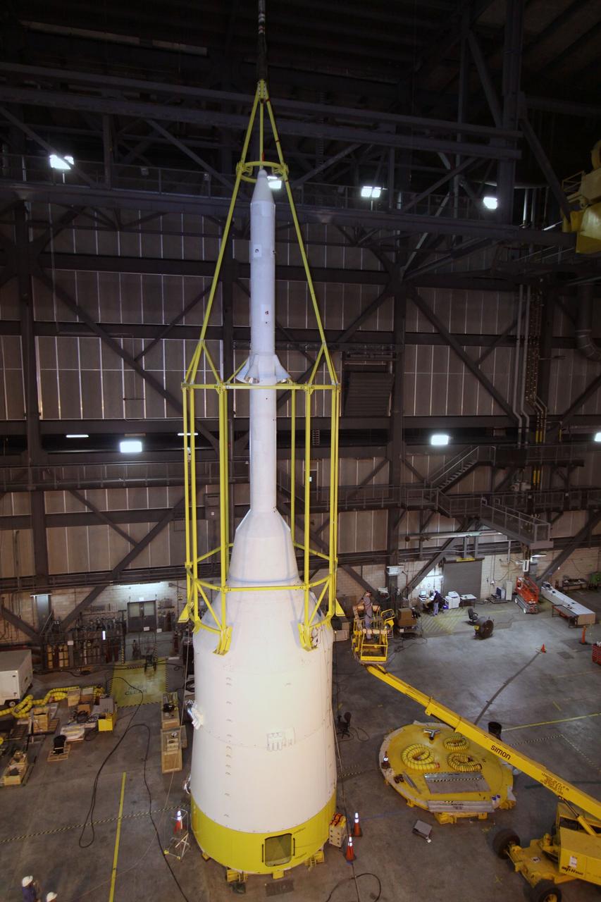 CAPE CANAVERAL, Fla. – In the Vehicle Assembly Building's High Bay 4, assembly of the Ares I-X rocket nears completion. The yellow framework, nicknamed the "birdcage," is lowered by crane over Super Stack 5.  The birdcage has the ability to lift and to stack and de-stack the Ares I-X rocket's Super Stack 5. Next, the stack will be lifted on top of the segments already in place on the mobile launcher platform, completing assembly of the rocket.  Five super stacks make up the rocket's upper stage that will be integrated with the four-segment solid rocket booster first stage. Ares I-X is the test vehicle for the Ares I, which is part of the Constellation Program to return men to the moon and beyond. The Ares I-X flight test is targeted for Oct. 31, pending formal NASA Headquarters approval. Photo credit: NASA/Jack Pfaller