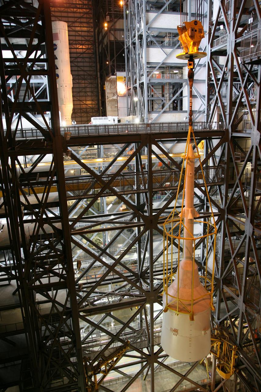 CAPE CANAVERAL, Fla. – In the Vehicle Assembly Building's High Bay 4, assembly of the Ares I-X rocket nears completion. The yellow framework, nicknamed the "birdcage," lifts Super Stack 5 toward an opening at the 16th floor crossover into the transfer aisle. The stack will be positioned on top of the segments already in place on the mobile launcher platform in High Bay 3, completing assembly of the 327-foot-tall rocket.  Five super stacks make up the rocket's upper stage that is integrated with the four-segment solid rocket booster first stage. Ares I-X is the test vehicle for the Ares I, which is part of the Constellation Program to return men to the moon and beyond. The Ares I-X flight test is targeted for Oct. 31, pending formal NASA Headquarters approval. Photo credit: NASA/Dimitri Gerondidakis