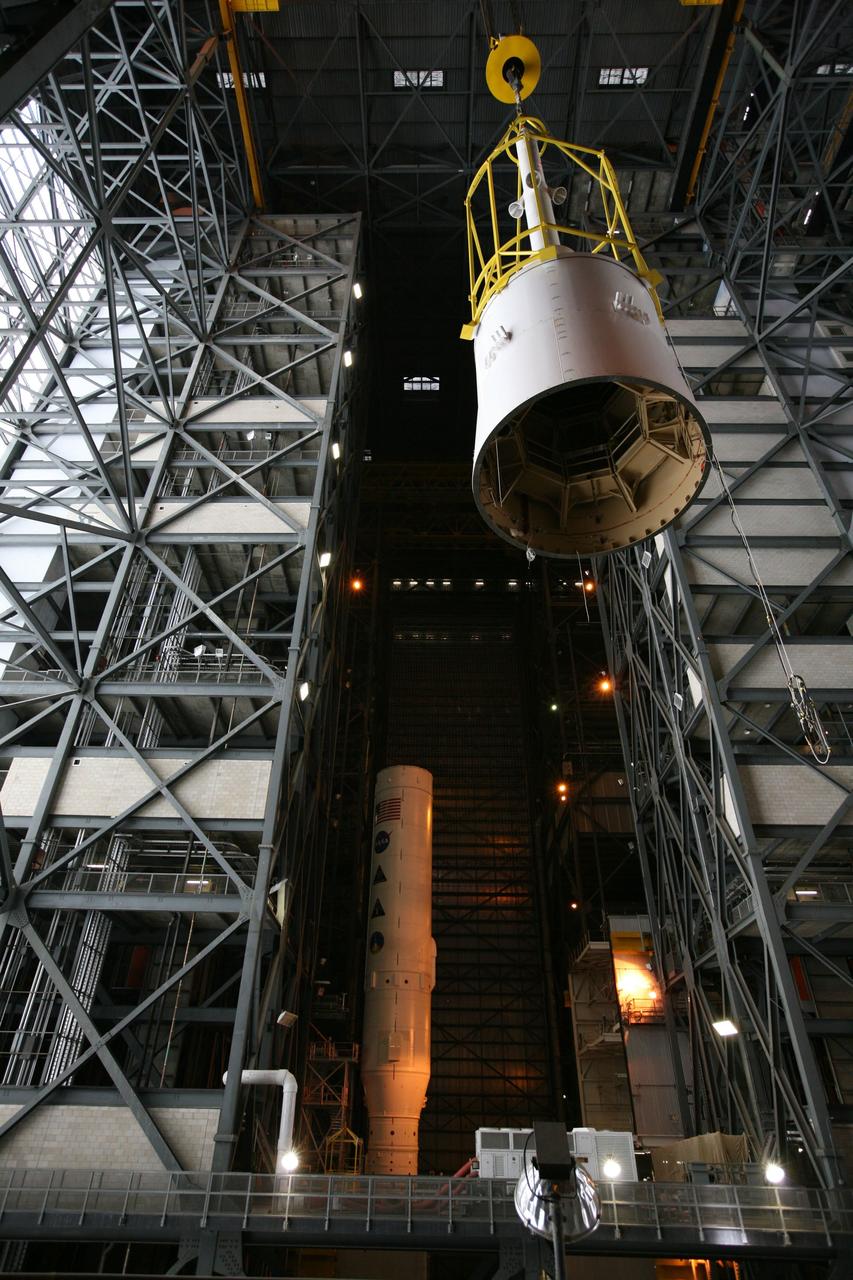 CAPE CANAVERAL, Fla. – In the Vehicle Assembly Building's transfer aisle, assembly of the Ares I-X rocket nears completion. The yellow framework, nicknamed the "birdcage," moves Super Stack 5 from High Bay 4 over the transfer aisle toward an opening at the 16th floor crossover in High Bay 3. The stack will be positioned on top of the segments already in place on the mobile launcher platform in High Bay 3, in the background, completing assembly of the 327-foot-tall rocket.  Five super stacks make up the rocket's upper stage that is integrated with the four-segment solid rocket booster first stage. Ares I-X is the test vehicle for the Ares I, which is part of the Constellation Program to return men to the moon and beyond. The Ares I-X flight test is targeted for Oct. 31, pending formal NASA Headquarters approval. Photo credit: NASA/Dimitri Gerondidakis