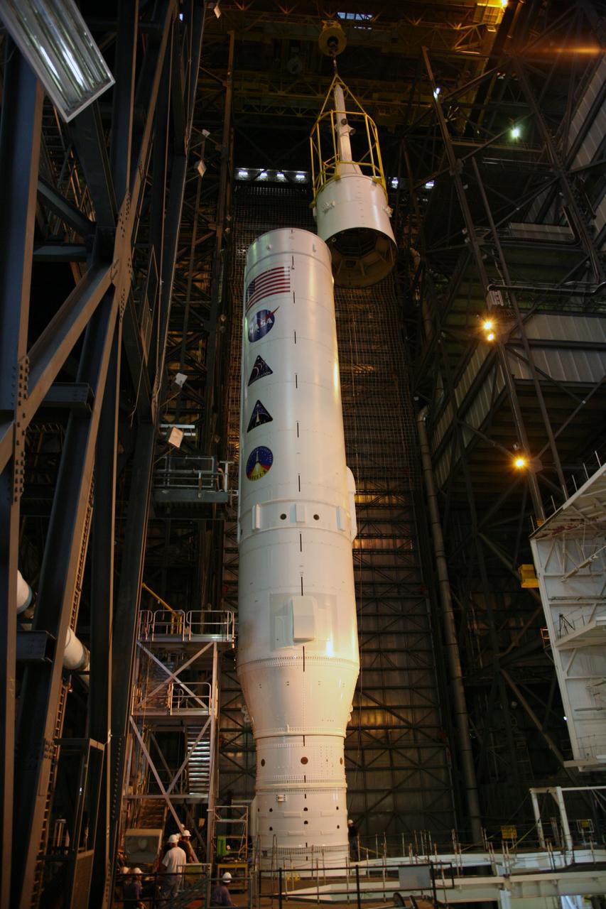 CAPE CANAVERAL, Fla. – In the Vehicle Assembly Building's High Bay 3, the yellow framework, nicknamed the "birdcage," lifts Super Stack 5 to the top of the Ares I-X segments already in place on the mobile launcher platform. Once in position, assembly of the Ares I-X rocket will be complete. The 327-foot-tall rocket is one of the largest processed in the bay, rivaling the height of the Apollo Program's 364-foot-tall Saturn V. Five super stacks make up the rocket's upper stage that is integrated with the four-segment solid rocket booster first stage. Ares I-X is the test vehicle for the Ares I, which is part of the Constellation Program to return men to the moon and beyond. The Ares I-X flight test is targeted for Oct. 31, pending formal NASA Headquarters approval. Photo credit: NASA/Dimitri Gerondidakis