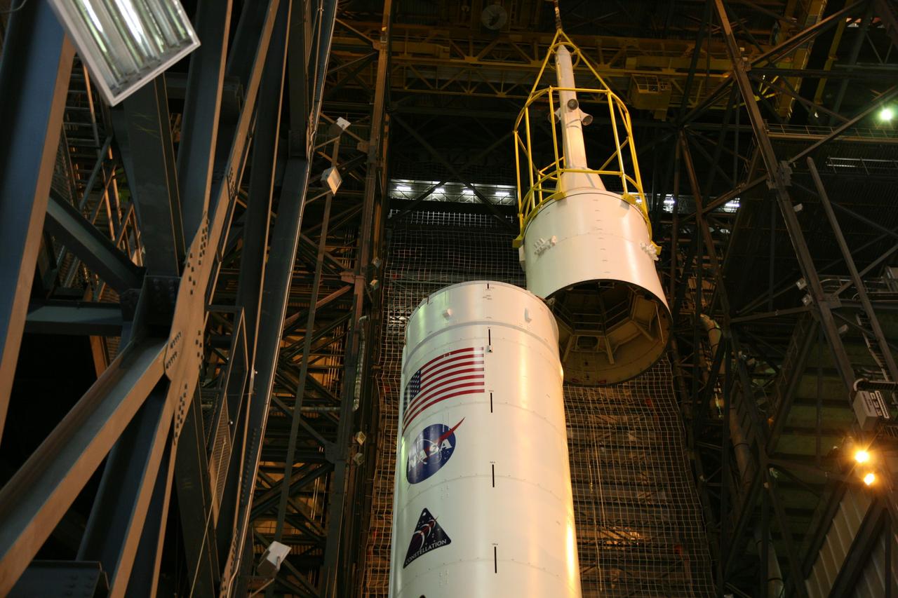 CAPE CANAVERAL, Fla. – In the Vehicle Assembly Building's High Bay 3, the yellow framework, nicknamed the "birdcage," lifts Super Stack 5 atop Super Stack 4.  Once in position, assembly of the Ares I-X rocket will be complete. The 327-foot-tall rocket is one of the largest processed in the bay, rivaling the height of the Apollo Program's 364-foot-tall Saturn V. Five super stacks make up the rocket's upper stage that is integrated with the four-segment solid rocket booster first stage. Ares I-X is the test vehicle for the Ares I, which is part of the Constellation Program to return men to the moon and beyond. The Ares I-X flight test is targeted for Oct. 31, pending formal NASA Headquarters approval. Photo credit: NASA/Dimitri Gerondidakis