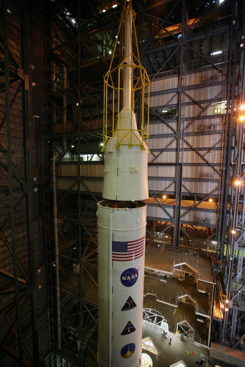 CAPE CANAVERAL, Fla. – In the Vehicle Assembly Building's High Bay 3, the yellow framework, nicknamed the "birdcage," lifts Super Stack 5 atop Super Stack 4.  Once in position, assembly of the Ares I-X rocket will be complete. The 327-foot-tall rocket is one of the largest processed in the bay, rivaling the height of the Apollo Program's 364-foot-tall Saturn V. Five super stacks make up the rocket's upper stage that is integrated with the four-segment solid rocket booster first stage. Ares I-X is the test vehicle for the Ares I, which is part of the Constellation Program to return men to the moon and beyond. The Ares I-X flight test is targeted for Oct. 31, pending formal NASA Headquarters approval. Photo credit: NASA/Dimitri Gerondidakis