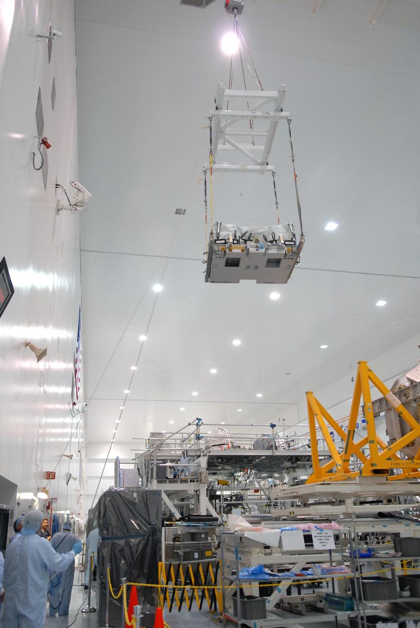 CAPE CANAVERAL, Fla. – In the Space Station Processing Facility at NASA's Kennedy Space Center in Florida, a battery charge-discharge unit is lifted by crane high above the hardware on the bay's floor. The unit is being moved toward an EXPRESS Logistics Carrier where it will be installed for flight. The carrier is part of the STS-129 payload on space shuttle Atlantis, which will deliver to the International Space Station two spare gyroscopes, two nitrogen tank assemblies, two pump modules, an ammonia tank assembly and a spare latching end effector for the station's robotic arm. STS-129 is targeted to launch Nov. 12. Photo credit: NASA/Jim Grossmann
