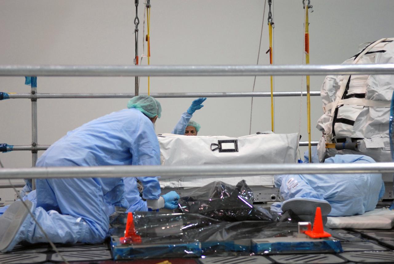 CAPE CANAVERAL, Fla. – In the Space Station Processing Facility at NASA's Kennedy Space Center in Florida, technicians install a battery charge-discharge unit on an EXPRESS Logistics Carrier for flight. The carrier is part of the STS-129 payload on space shuttle Atlantis, which will deliver to the International Space Station two spare gyroscopes, two nitrogen tank assemblies, two pump modules, an ammonia tank assembly and a spare latching end effector for the station's robotic arm. STS-129 is targeted to launch Nov. 12. Photo credit: NASA/Jim Grossmann