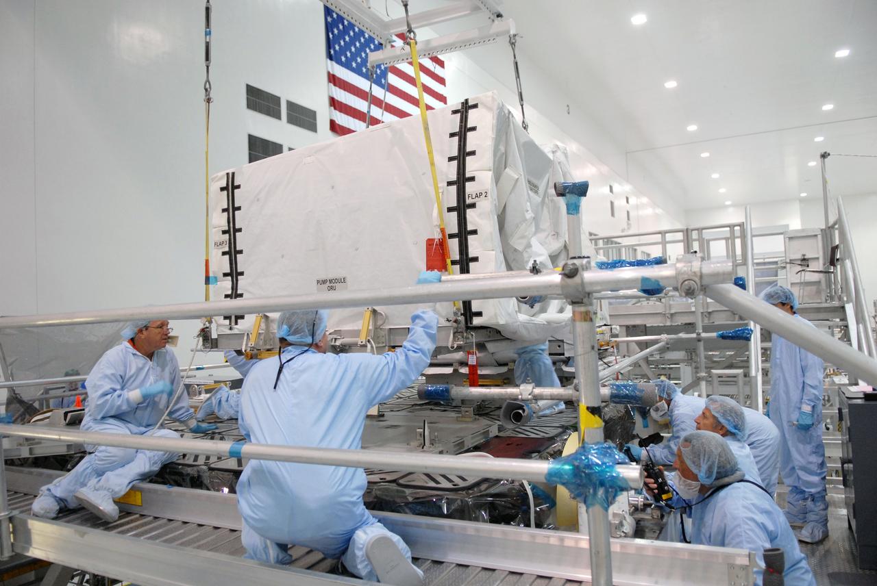 CAPE CANAVERAL, Fla. – In the space Station Processing Facility at NASA's Kennedy Space Center in Florida, technicians watch closely as the pump module orbital replacement unit is lowered onto the Express Logistics Carrier 1, or ELC-1, for installation. The carrier is part of the STS-129 payload on space shuttle Atlantis, which will deliver to the International Space Station two spare gyroscopes, two nitrogen tank assemblies, two pump modules, an ammonia tank assembly and a spare latching end effector for the station's robotic arm. STS-129 is targeted to launch Nov. 12. Photo credit: NASA/Jim Grossmann