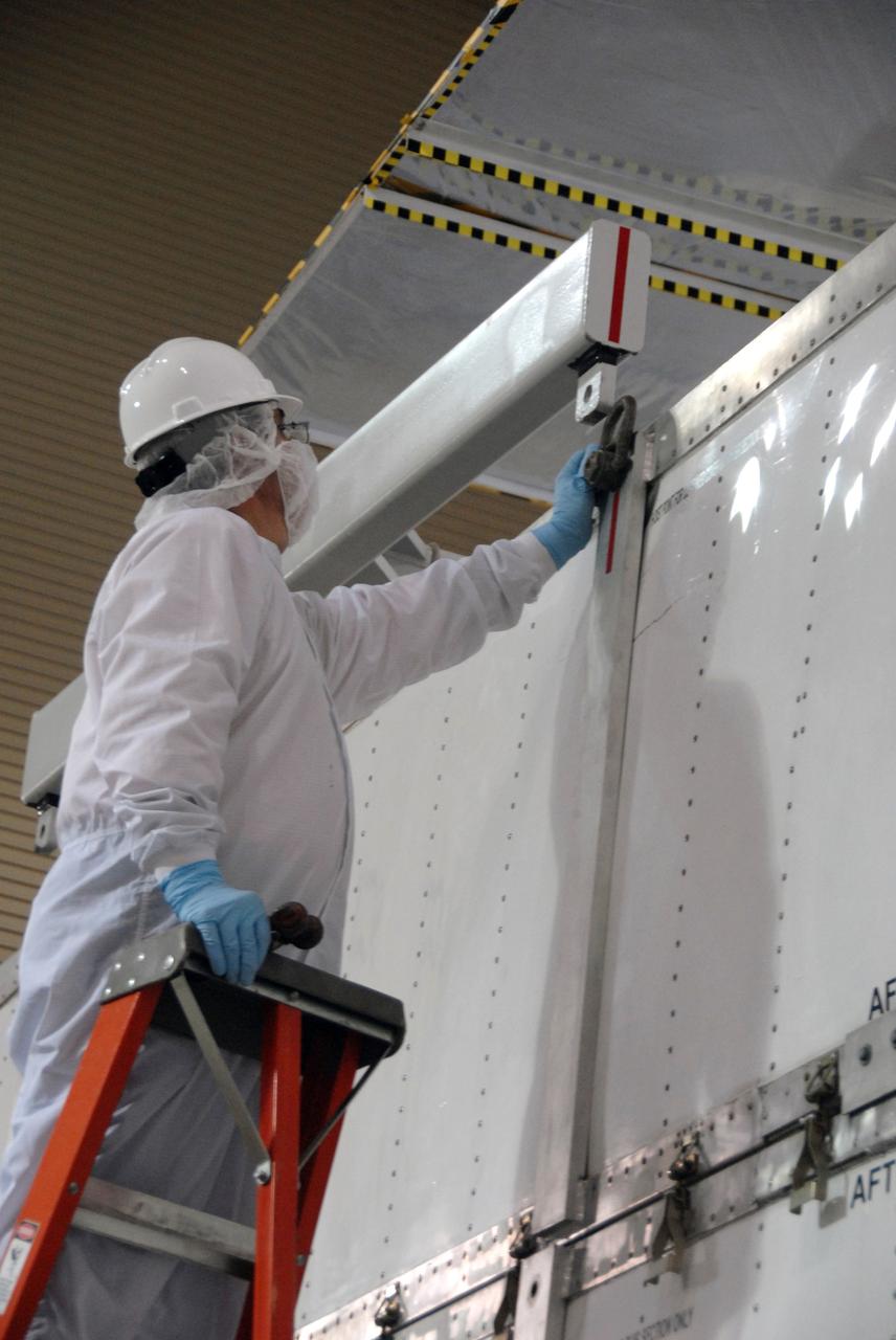 VANDENBERG AIR FORCE BASE, Calif. -- In the Astrotech payload processing facility at Vandenberg Air Force Base in California, workers attach the overhead crane onto the shipping container to remove it from around NASA's Wide-field Infrared Survey Explorer, or WISE, spacecraft. The satellite will survey the entire sky at infrared wavelengths, creating a cosmic clearinghouse of hundreds of millions of objects,  which will be catalogued, providing a vast storehouse of knowledge about the solar system, the Milky Way, and the universe. Launch is scheduled no earlier than Dec. 10.  Photo credit: NASA/Doug Kolkow, VAFB