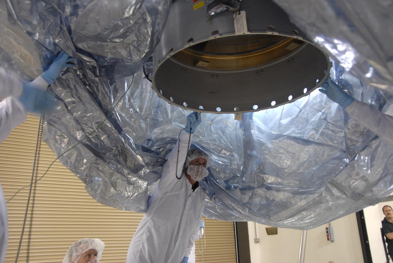 VANDENBERG AIR FORCE BASE, Calif. -- In the Astrotech payload processing facility at Vandenberg Air Force Base in California, workers check the underside of NASA's Wide-field Infrared Survey Explorer, or WISE, spacecraft before it is lowered onto a stand. The satellite will survey the entire sky at infrared wavelengths, creating a cosmic clearinghouse of hundreds of millions of objects,  which will be catalogued, providing a vast storehouse of knowledge about the solar system, the Milky Way, and the universe. Launch is scheduled no earlier than Dec. 10.  Photo credit: NASA/Doug Kolkow, VAFB