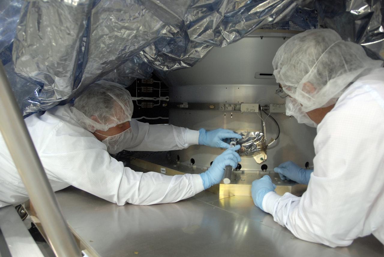 VANDENBERG AIR FORCE BASE, Calif. -- In the Astrotech payload processing facility at Vandenberg Air Force Base in California, workers check the attachment of NASA's Wide-field Infrared Survey Explorer, or WISE, spacecraft to the stand. The satellite will survey the entire sky at infrared wavelengths, creating a cosmic clearinghouse of hundreds of millions of objects, which will be catalogued, providing a vast storehouse of knowledge about the solar system, the Milky Way, and the universe. Launch is scheduled no earlier than Dec. 10. Photo credit: NASA/Doug Kolkow, VAFB