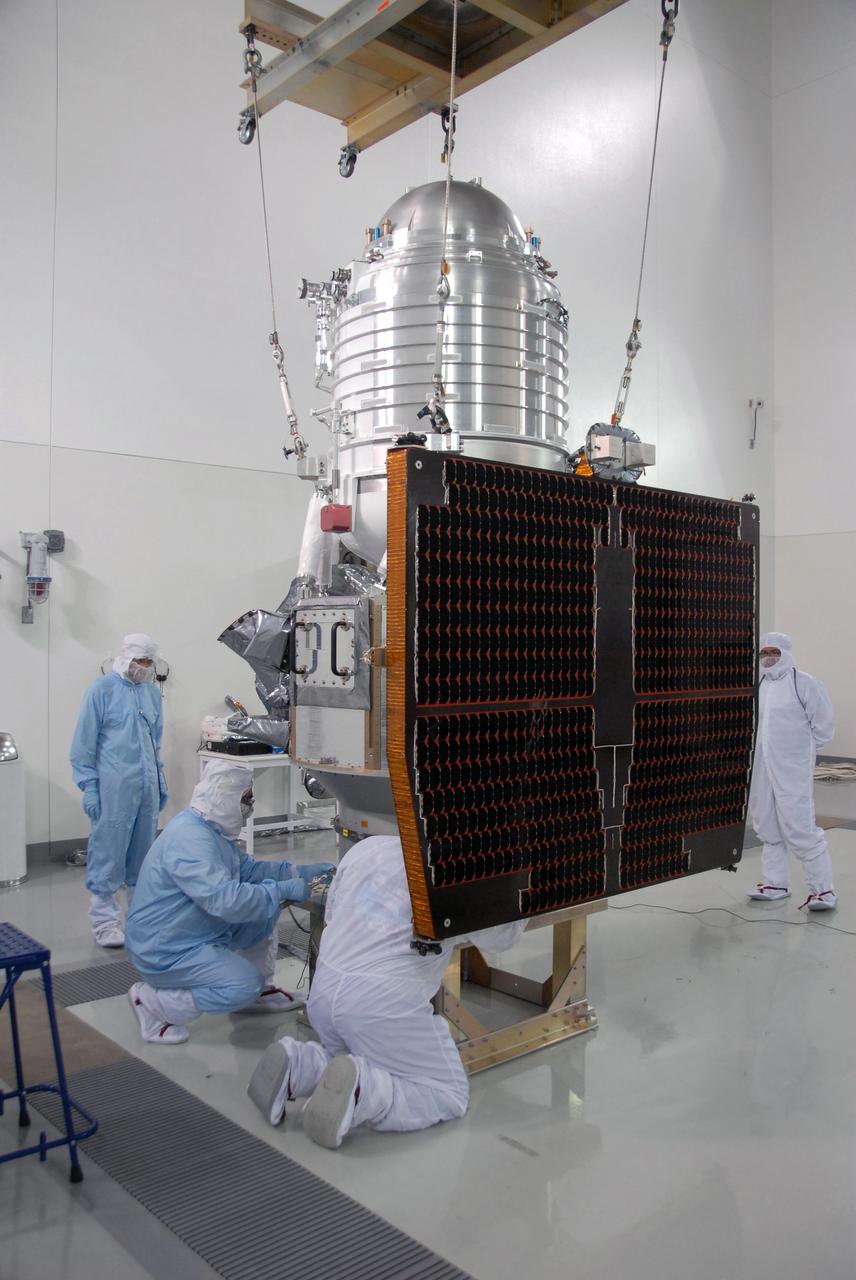VANDENBERG AIR FORCE BASE, Calif. -- At Vandenberg Air Force Base's Astrotech processing facility in California, workers secure NASA's Wide-field Infrared Survey Explorer, or WISE, spacecraft onto a work stand.  At right is seen the fixed panel solar array.  The satellite will survey the entire sky at infrared wavelengths, creating a cosmic clearinghouse of hundreds of millions of objects,  which will be catalogued, providing a vast storehouse of knowledge about the solar system, the Milky Way, and the universe. Launch is scheduled no earlier than Dec. 10.  Photo credit: NASA/Moore, VAFB