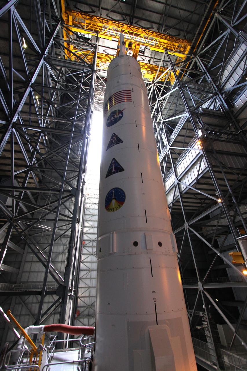 CAPE CANAVERAL, Fla. – The 327-foot tall Ares I-X rocket stretches into the upper regions of NASA Kennedy Space Center's Vehicle Assembly Building.  The rocket is stacked on the mobile launcher platform in High Bay 3.  Mission, program and NASA decals are lined up on the stack below the U.S. flag.  Five super stacks make up the upper stage that are integrated with the four-segment solid rocket booster first stage below.  Ares I-X is the test vehicle for the Ares I, which is part of the Constellation Program to return men to the moon and beyond. The Ares I-X flight test is targeted for  Oct. 31.  Photo credit: NASA/Jack Pfaller