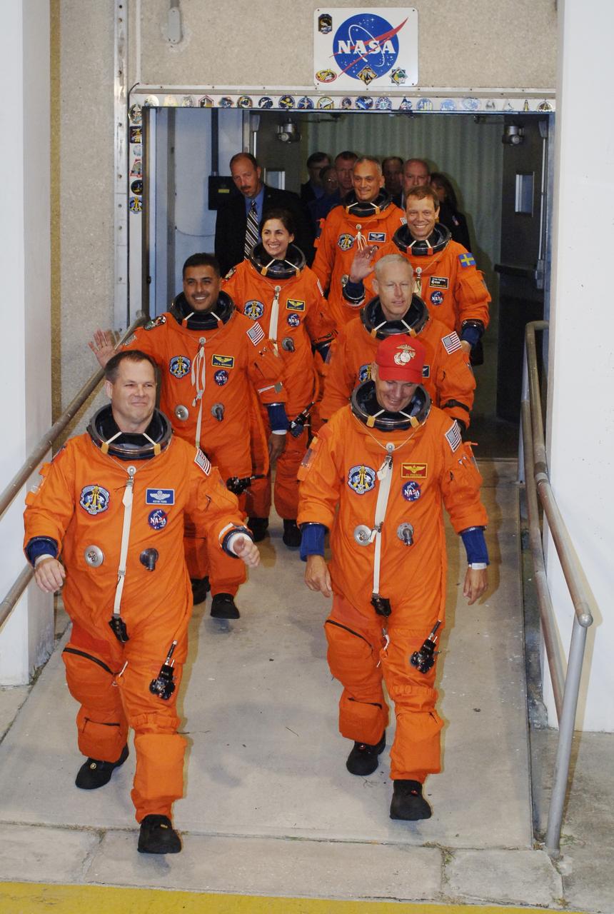 CAPE CANAVERAL, Fla. – The STS-128 crew members eagerly exit NASA Kennedy Space Center's Operations and Checkout Building to head to the Astrovan for the 3.4-mile drive to Launch Pad 39A. Clockwise from left are Pilot Kevin Ford, Mission Specialists Jose Fernandez, Nicole Stott, Danny Olivas, Christer Fuglesang and Patrick Forrester, and Commander Rick Sturckow. At the pad, the astronauts will complete their suitup and enter space shuttle Discovery for the 1:36 a.m. EDT liftoff. The 13-day mission will deliver more than 7 tons of supplies, science racks and equipment, as well as additional environmental hardware to sustain six crew members on the International Space Station. The equipment includes a freezer to store research samples, a new sleeping compartment and the COLBERT treadmill. The mission is the 128th in the Space Shuttle Program, the 37th flight of Discovery and the 30th station assembly flight. Photo credit: NASA/Kim Shiflett