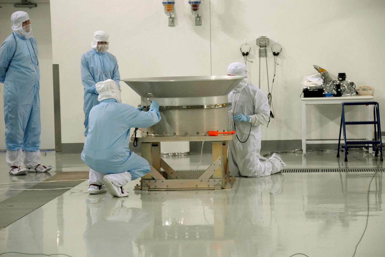 VANDENBERG AIR FORCE BASE, Calif. -- At Vandenberg Air Force Base's Astrotech processing facility in California, technicians prepare to mate the flight conical adapter and soft ride to the test payload attach fitting clampband on the spacecraft test stand. The satellite will survey the entire sky at infrared wavelengths, creating a cosmic clearinghouse of hundreds of millions of objects, which will be catalogued, providing a vast storehouse of knowledge about the solar system, the Milky Way, and the universe. Launch is scheduled no earlier than Dec. 7. Photo credit: NASA/Doug Kolkow