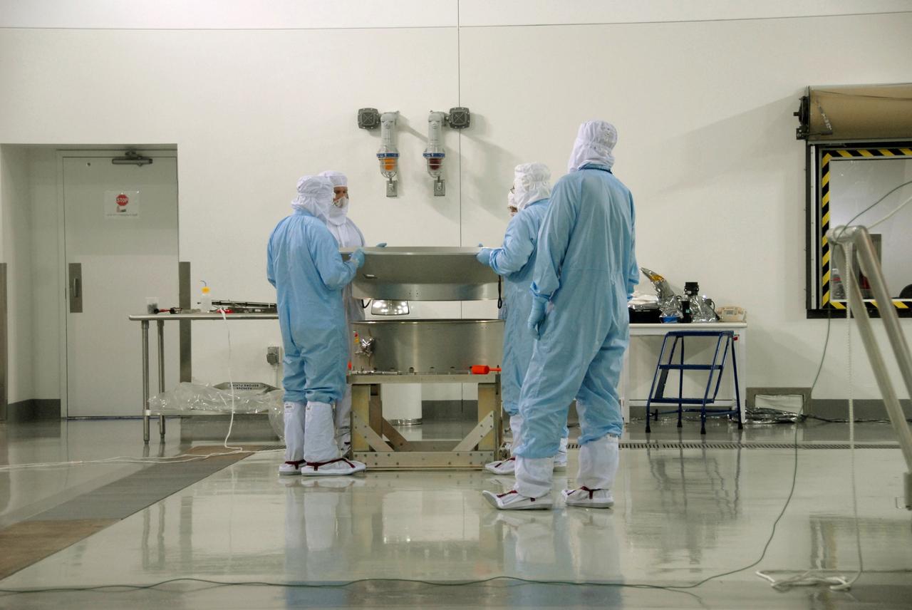 VANDENBERG AIR FORCE BASE, Calif. -- At Vandenberg Air Force Base's Astrotech processing facility in California, technicians prepare to mate the flight conical adapter and soft ride to the test payload attach fitting clampband on the spacecraft test stand. The satellite will survey the entire sky at infrared wavelengths, creating a cosmic clearinghouse of hundreds of millions of objects, which will be catalogued, providing a vast storehouse of knowledge about the solar system, the Milky Way, and the universe. Launch is scheduled no earlier than Dec. 7. Photo credit: NASA/Doug Kolkow