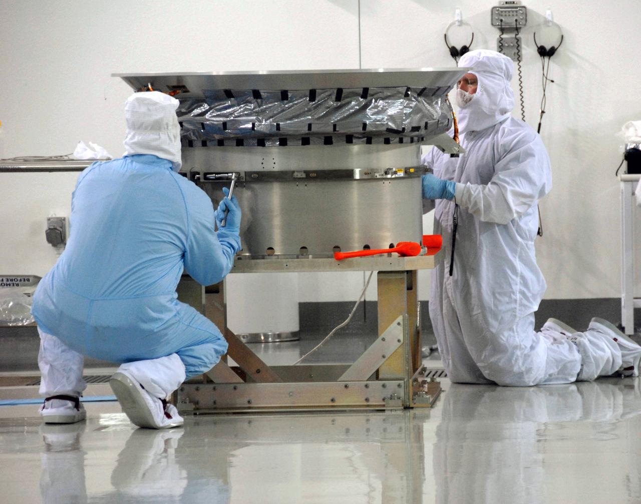 VANDENBERG AIR FORCE BASE, Calif. -- At Vandenberg Air Force Base's Astrotech processing facility in California, technicians working on NASA's Wide-field Infrared Survey Explorer, or WISE, spacecraft complete attaching the clampband on the test payload attach fitting. The satellite will survey the entire sky at infrared wavelengths, creating a cosmic clearinghouse of hundreds of millions of objects, which will be catalogued, providing a vast storehouse of knowledge about the solar system, the Milky Way, and the universe. Launch is scheduled no earlier than Dec. 7. Photo credit: NASA/Doug Kolkow