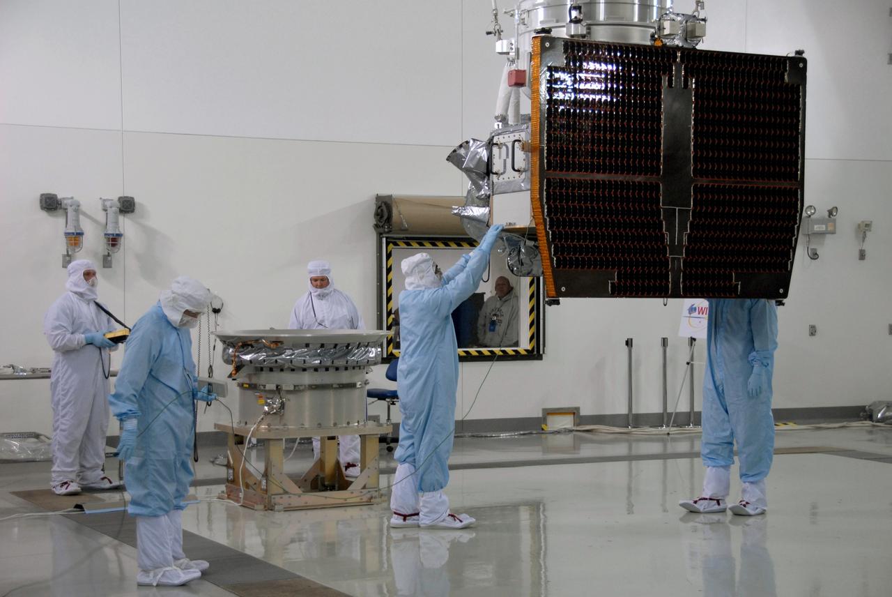 VANDENBERG AIR FORCE BASE, Calif. -- At Vandenberg Air Force Base's Astrotech processing facility in California, technicians help guide NASA's Wide-field Infrared Survey Explorer, or WISE, spacecraft to the flight conical adapter and test stand. The satellite will survey the entire sky at infrared wavelengths, creating a cosmic clearinghouse of hundreds of millions of objects, which will be catalogued, providing a vast storehouse of knowledge about the solar system, the Milky Way, and the universe. Launch is scheduled no earlier than Dec. 7. Photo credit: NASA/Doug Kolkow
