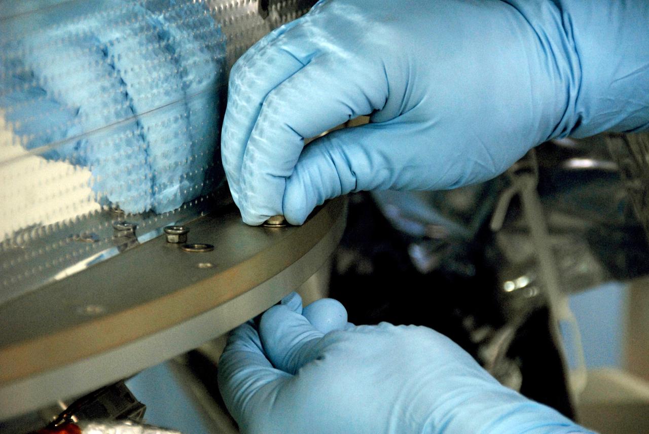 VANDENBERG AIR FORCE BASE, Calif. -- At Vandenberg Air Force Base's Astrotech processing facility in California, a technician fastens NASA's Wide-field Infrared Survey Explorer, or WISE, spacecraft onto the flight conical adapter and test stand. The satellite will survey the entire sky at infrared wavelengths, creating a cosmic clearinghouse of hundreds of millions of objects, which will be catalogued, providing a vast storehouse of knowledge about the solar system, the Milky Way, and the universe. Launch is scheduled no earlier than Dec. 7. Photo credit: NASA/Doug Kolkow