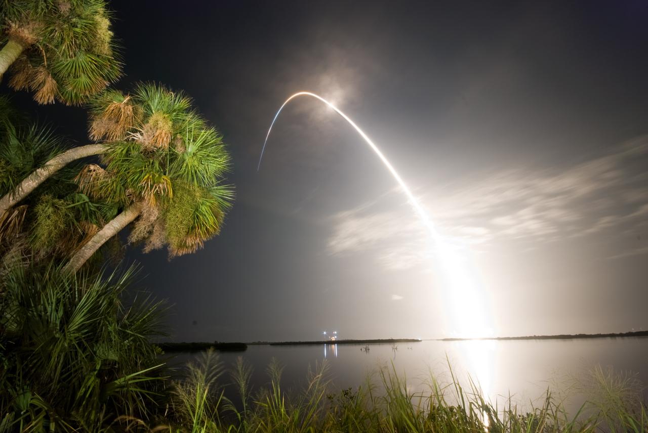 CAPE CANAVERAL, Fla. –   Viewed from the Banana River Viewing Site at NASA's Kennedy Space Center in Florida, space shuttle Discovery arcs through a cloud-brushed sky lighted by the trail of fire after launch on the STS-128 mission.   Liftoff from Launch Pad 39A was on time at 11:59 p.m. EDT. The first launch attempt on Aug. 24 was postponed due to unfavorable weather conditions.  The second attempt on Aug. 25 also was postponed due to an issue with a valve in space shuttle Discovery's main propulsion system.  The STS-128 mission is the 30th International Space Station assembly flight and the 128th space shuttle flight. The 13-day mission will deliver more than 7 tons of supplies, science racks and equipment, as well as additional environmental hardware to sustain six crew members on the International Space Station. The equipment includes a freezer to store research samples, a new sleeping compartment and the COLBERT treadmill.  Photo credit: NASA/Ben Cooper