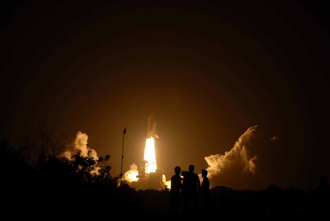 CAPE CANAVERAL, Fla. –  Riding a tower of flames, space shuttle Discovery lights the night sky as it races toward space on the STS-128 mission.  In the foreground are a few of the dozens of media documenting the event at NASA's Kennedy Space Center in Florida.  Liftoff from Launch Pad 39A was on time at 11:59 p.m. EDT. The first launch attempt on Aug. 24 was postponed due to unfavorable weather conditions.  The second attempt on Aug. 25 also was postponed due to an issue with a valve in space shuttle Discovery's main propulsion system.  The STS-128 mission is the 30th International Space Station assembly flight and the 128th space shuttle flight. The 13-day mission will deliver more than 7 tons of supplies, science racks and equipment, as well as additional environmental hardware to sustain six crew members on the International Space Station. The equipment includes a freezer to store research samples, a new sleeping compartment and the COLBERT treadmill.  Photo credit: NASA/Laurel Lichtenberger