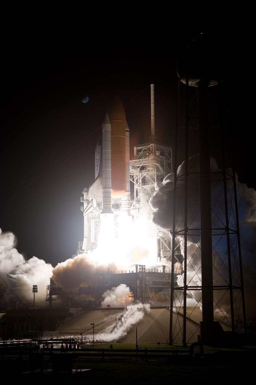 CAPE CANAVERAL, Fla. –  Riding columns of flames, space shuttle Discovery lights the night sky as it leaps from Launch Pad 39A at NASA's Kennedy Space Center in Florida on the STS-128 mission.  The moon, visible above and left of the shuttle, catches the glow. Liftoff was on time at 11:59 p.m. EDT. The first launch attempt on Aug. 24 was postponed due to unfavorable weather conditions.  The second attempt on Aug. 25 also was postponed due to an issue with a valve in space shuttle Discovery's main propulsion system.  The STS-128 mission is the 30th International Space Station assembly flight and the 128th space shuttle flight. The 13-day mission will deliver more than 7 tons of supplies, science racks and equipment, as well as additional environmental hardware to sustain six crew members on the International Space Station. The equipment includes a freezer to store research samples, a new sleeping compartment and the COLBERT treadmill.  Photo credit: NASA/Sandra Joseph-Kevin O'Connell
