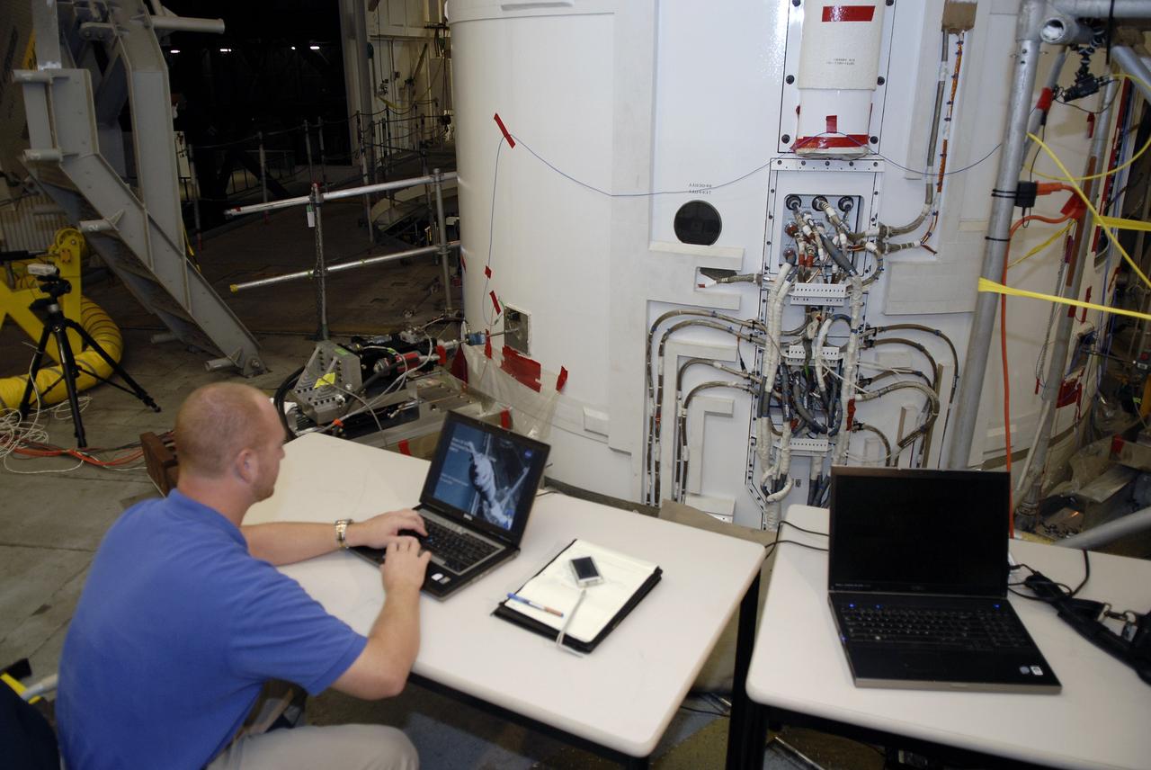 CAPE CANAVERAL, Fla. – In the Vehicle Assembly Building's High Bay 4 at NASA's Kennedy Space Center in Florida, a worker seated at the table monitors data collected during a sway test on the Ares I-X launch vehicle. The test is simulating conditions the rocket could experience during rollout to Launch Pad 39B, wind conditions at the pad and first-stage ignition. During the test, vibrations are mechanically induced into the rocket by four hydraulic shakers and a sway is manually introduced for lateral motion to measure the vehicle's response. A total of 44 accelerometers are installed on the flight test vehicle that required more than 27,000 feet of cable. Part of the Constellation Program, the Ares I-X is the test vehicle for the Ares I, which is the essential core of a space transportation system that eventually will carry crewed missions back to the moon, on to Mars and out into the solar system . The Ares I-X flight test is targeted for Oct. 31. Photo credit: NASA/Kim Shiflett