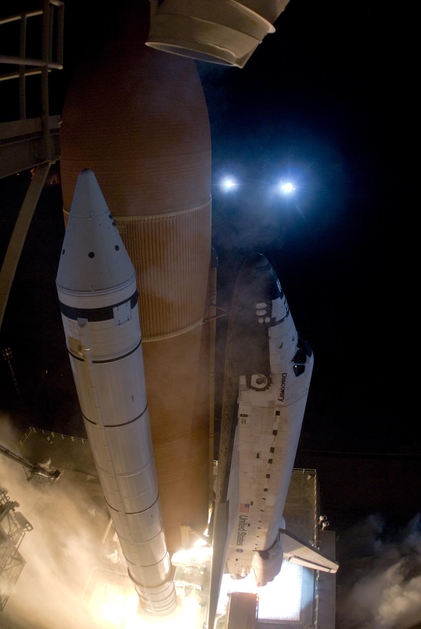CAPE CANAVERAL, Fla. – Water from the rainbirds floods the mobile launcher platform as space shuttle Discovery rises from NASA Kennedy Space Center's Launch pad 39A on the STS-128 mission. The water helps with sound suppression.  Above Discovery's nose are two of the xenon lights that surround the pad.   Liftoff from Launch Pad 39A was on time at 11:59 p.m. EDT. The first launch attempt on Aug. 24 was postponed due to unfavorable weather conditions. The second attempt on Aug. 25 also was postponed due to an issue with a valve in space shuttle Discovery's main propulsion system. The STS-128 mission is the 30th International Space Station assembly flight and the 128th space shuttle flight. The 13-day mission will deliver more than 7 tons of supplies, science racks and equipment, as well as additional environmental hardware to sustain six crew members on the International Space Station. The equipment includes a freezer to store research samples, a new sleeping compartment and the COLBERT treadmill. Photo credit: NASA/Tony Gray-Tom Farrar