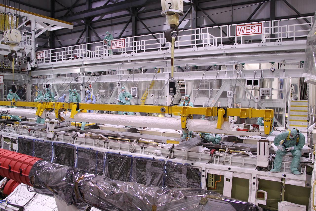 CAPE CANAVERAL, Fla. – In NASA Kennedy Space Center's Orbiter Processing Facility bay 2, workers watch the movement of space shuttle Endeavour's Orbiter Boom Sensor System as it is lowered into the payload bay. The OBSS is a 50-foot boom with a laser and cameras on it that astronauts use to inspect a shuttle's heat shield while in orbit. After returning from the STS-127 mission July 31, 2009, Endeavour now is being processed for the STS-130 mission targeted for Feb. 4, 2010. Endeavour will deliver to the International Space Station the Tranquility pressurized module that will provide room for many of the station's life support systems. Photo credit: NASA/Jack Pfaller