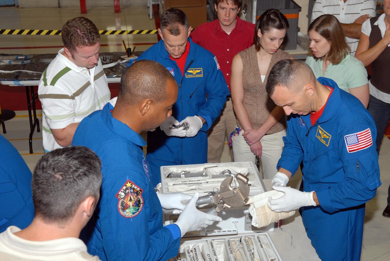CAPE CANAVERAL, Fla. – In NASA Kennedy Space Center's Orbiter Processing Facility 1, STS-129 crew members open some of the equipment that will be used on the mission.  From left are Mission Specialist Leland Melvin, Commander Charles Hobaugh and Mission Specialist Randy Bresnik. The crew is at Kennedy for a Crew Equipment Interface Test, which provides hands-on training and observation of shuttle and flight hardware.  Space shuttle Atlantis' STS-129 mission is targeted to launch Nov. 12.  Photo credit: NASA/Jim Grossmann