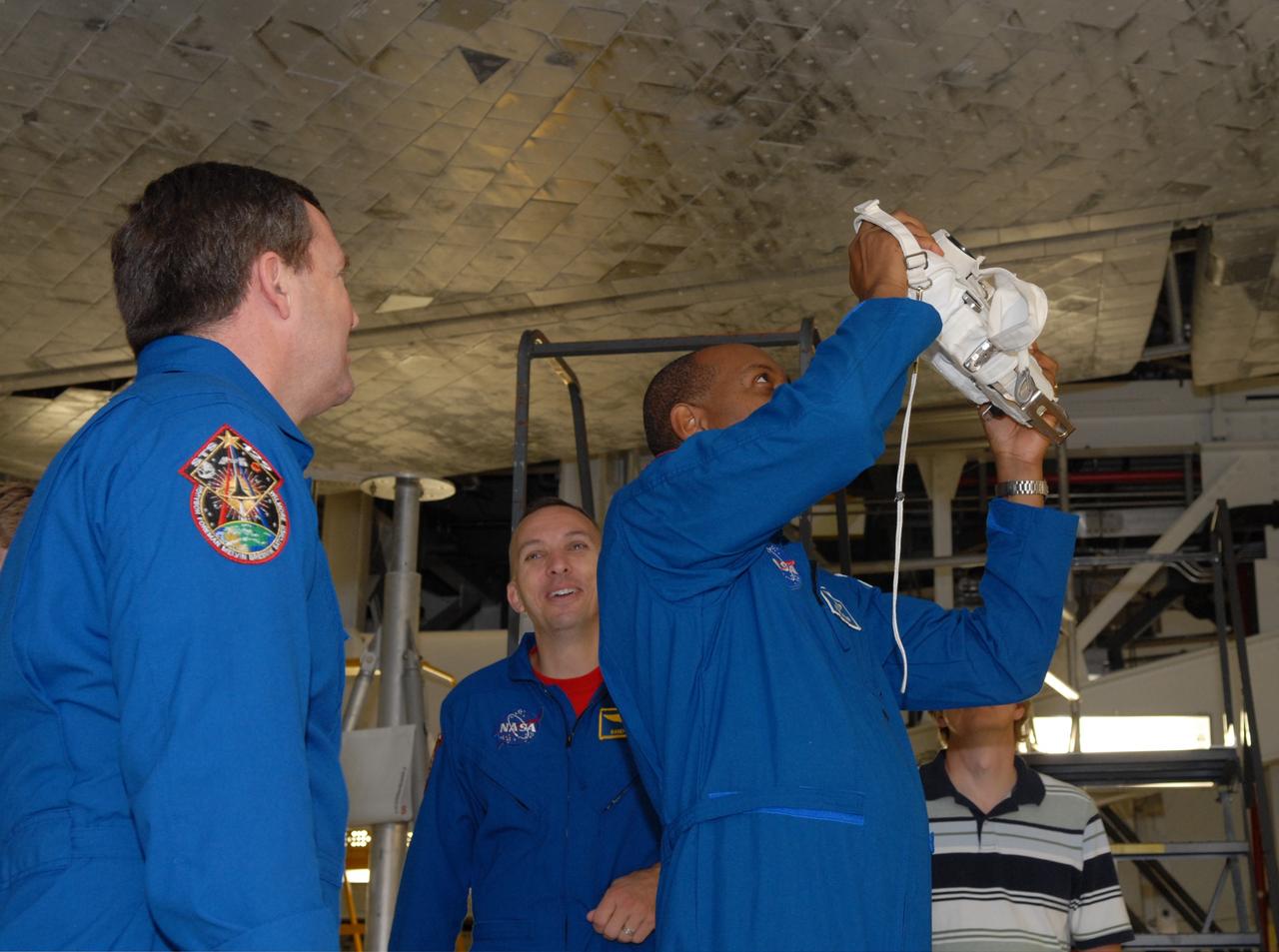 CAPE CANAVERAL, Fla. – In NASA Kennedy Space Center's Orbiter Processing Facility 1, STS-129 crew members take a close look at some of the tiles on the underside of space shuttle Atlantis. At left are Mission Specialists Michael Foreman and Randy Bresnik. At right, Mission Specialist Robert Satcher practices focusing a camera that will be used on the mission. The crew is at Kennedy for a Crew Equipment Interface Test, which provides hands-on training and observation of shuttle and flight hardware. Atlantis' STS-129 mission is targeted to launch Nov. 12. Photo credit: NASA/Jim Grossmann