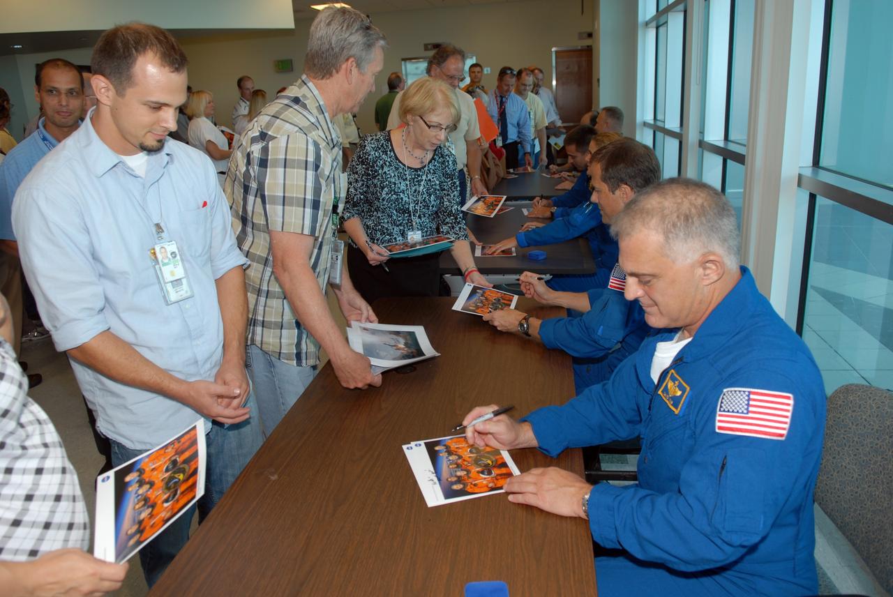CAPE CANAVERAL, Fla. –  STS-127 crew members autograph mementos for attendees following a presentation about the astronauts' experiences on the mission.  Seated top to bottom at right are Commander Mark Polansky, Pilot Doug Hurley, and Mission Specialists Christopher Cassidy, Julie Payette, Tom Marshburn and Dave Wolf.  The STS-127 mission was the final of three flights dedicated to the assembly of the Japanese Kibo laboratory complex on the International Space Station.  The crew launched on space shuttle Endeavour on July 15 and returned July 31.  Photo credit: NASA/Jim Grossmann
