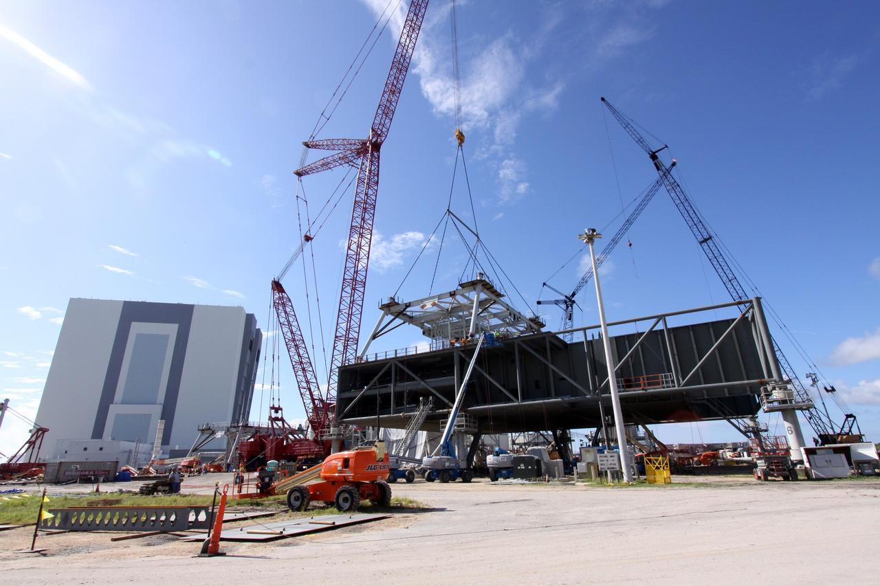 CAPE CANAVERAL, Fla. – Progress is evident in the Constellation Program at NASA's Kennedy Space Center in Florida, as the first section of a tower is lowered by crane onto a new mobile launcher, or ML.    The tower of the mobile launcher will have multiple platforms for personnel access and will be approximately 345 feet tall. The launcher is being built at the mobile launcher park site area located north of Kennedy's Vehicle Assembly Building to support the Ares I rocket. The ML will provide a base to launch the Ares I which will transport the Orion crew exploration vehicle, its crew and cargo to low Earth orbit. The base is being made lighter than space shuttle mobile launcher platforms so the crawler-transporter can pick up the heavier load of the tower and taller rocket.  Photo credit: NASA/Jack Pfaller
