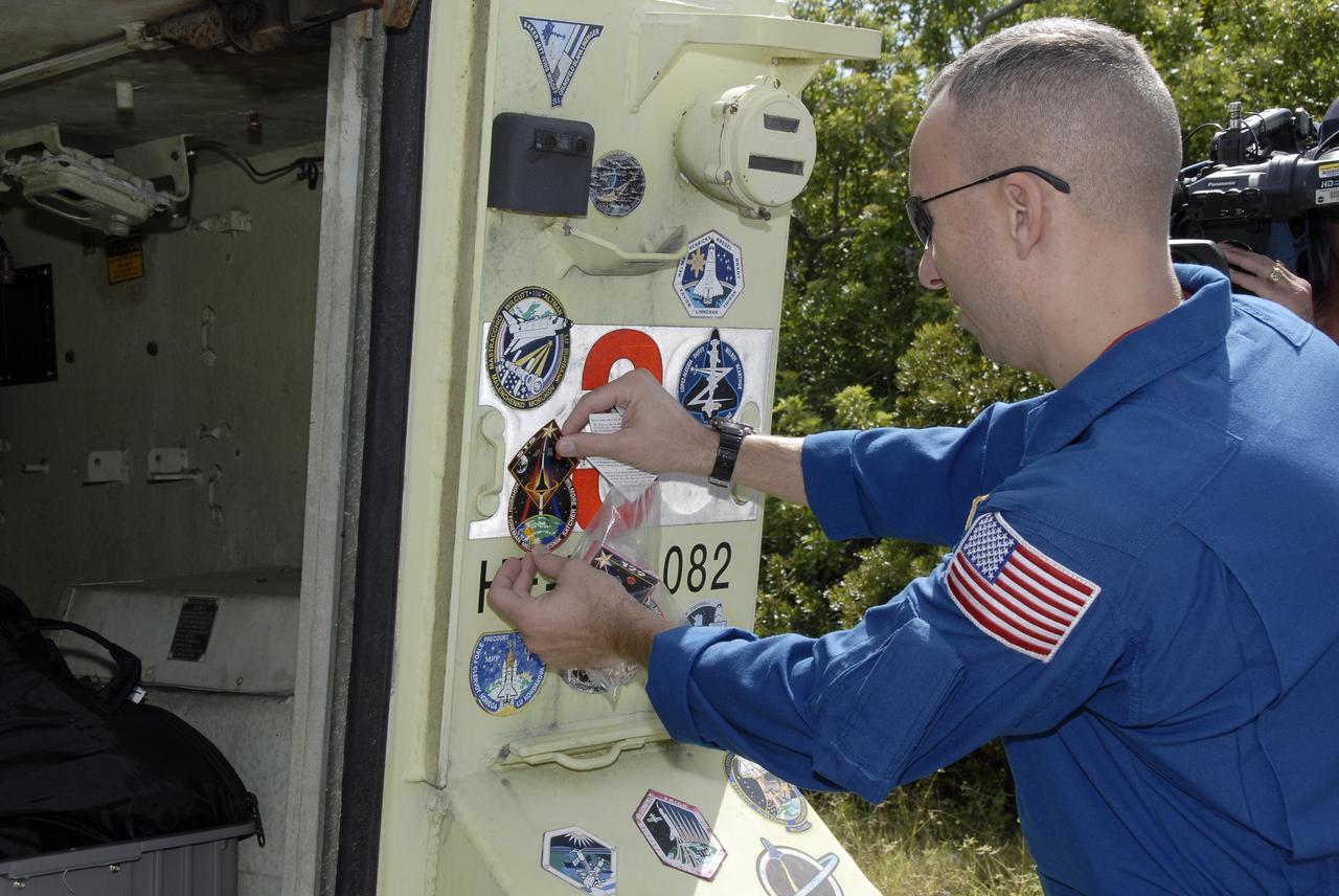 CAPE CANAVERAL, Fla. - At NASA's Kennedy Space Center in Florida, STS-129 Mission Specialist Randy Bresnik affixes his mission's logo to an M113 armored personnel carrier.    The M113 is kept at the foot of the launch pad in case an emergency egress from the vicinity of the pad is needed.  The crew members of space shuttle Atlantis' STS-129 mission are at Kennedy for training related to their launch dress rehearsal, the Terminal Countdown Demonstration Test.  Launch of Atlantis on its STS-129 mission to the International Space Station is targeted for Nov. 16. For information on the STS-129 mission objectives and crew, visit http://www.nasa.gov/mission_pages/shuttle/shuttlemissions/sts129/index.html. Photo credit: NASA/Kim Shiflett