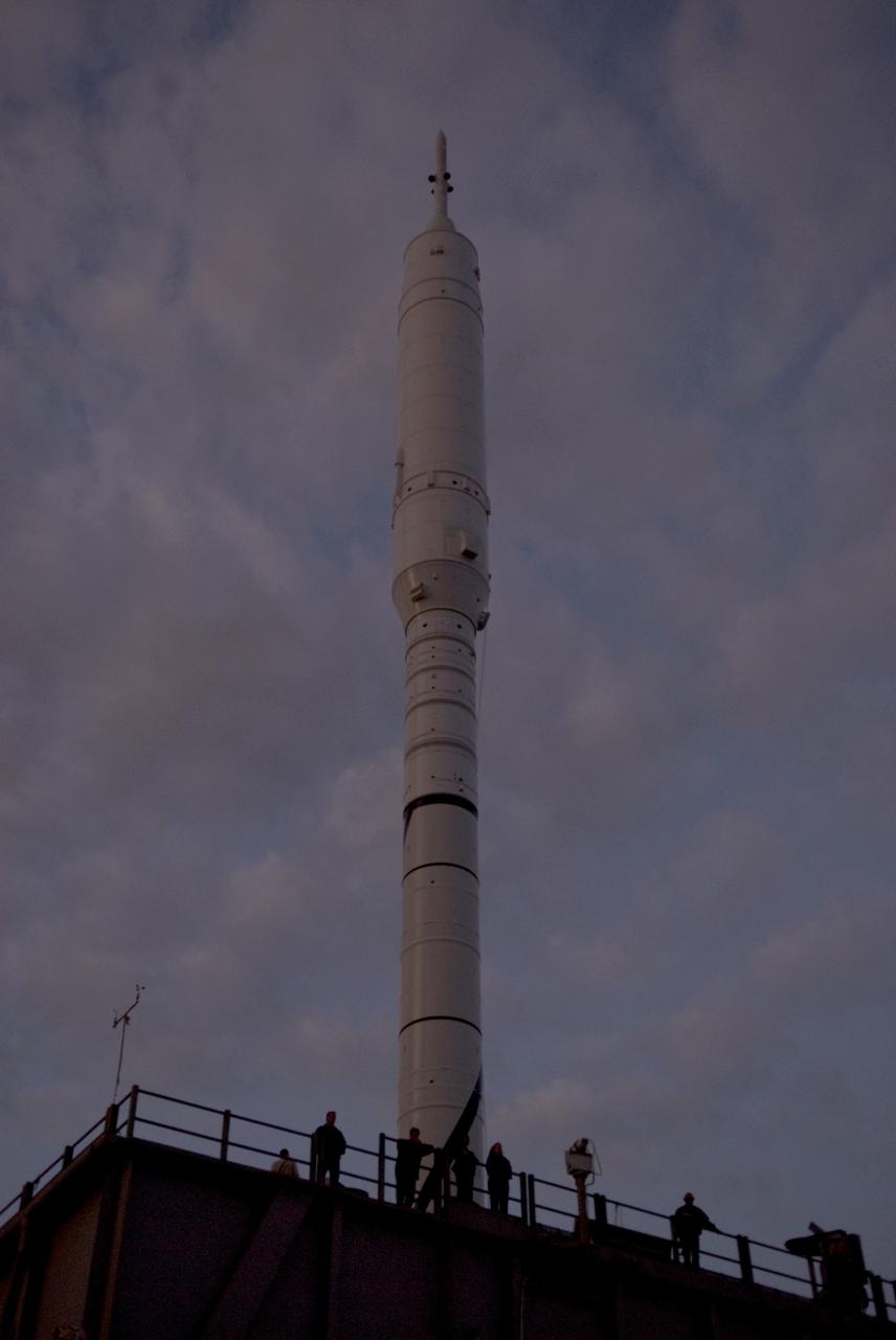 CAPE CANAVERAL, Fla. – As the sun rises over NASA's Kennedy Space Center in Florida, workers ride on the mobile launcher platform to Launch Pad 39B with the 327-foot-tall Ares I-X rocket.    The test rocket left the Vehicle Assembly Building at 1:39 a.m. EDT on its 4.2-mile trek to the pad and was "hard down" on the pad’s pedestals at 9:17 a.m.  The transfer of the pad from the Space Shuttle Program to the Constellation Program took place May 31. Modifications made to the pad include the removal of shuttle unique subsystems, such as the orbiter access arm and a section of the gaseous oxygen vent arm, along with the installation of three 600-foot lightning towers, access platforms, environmental control systems and a vehicle stabilization system.  Part of the Constellation Program, the Ares I-X is the test vehicle for the Ares I. The Ares I-X flight test is targeted for Oct. 27. For information on the Ares I-X vehicle and flight test, visit http://www.nasa.gov/aresIX.  Photo credit: NASA/Kim Shiflett