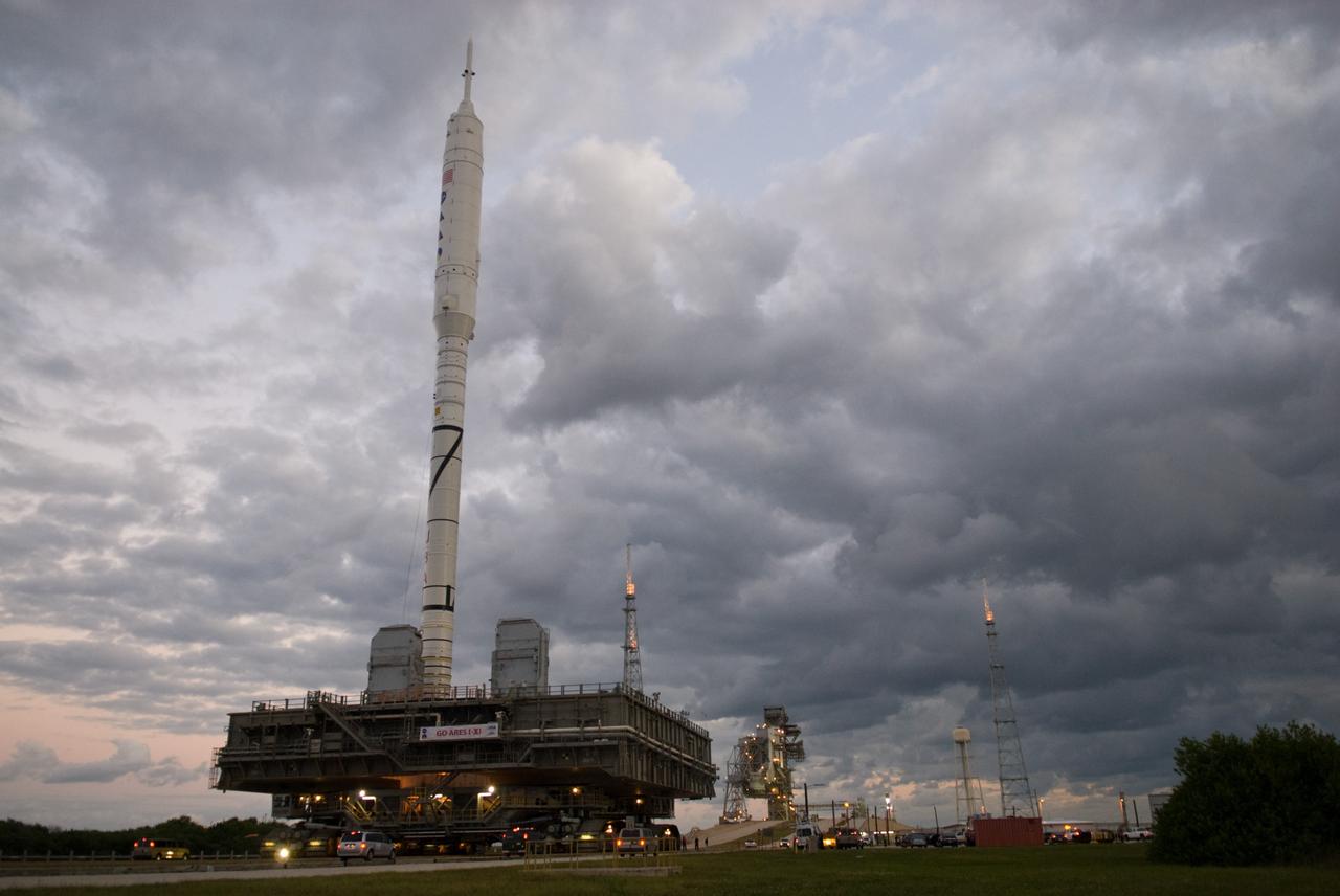 CAPE CANAVERAL, Fla. – As the sun rises over Launch Pad 39B at NASA's Kennedy Space Center in Florida, the 327-foot-tall Ares I-X rocket, secured to a mobile launcher platform, prepares to climb the five percent grade of the crawlerway to the top of the pad.    The test rocket left the Vehicle Assembly Building at 1:39 a.m. EDT on its 4.2-mile trek to the pad and was "hard down" on the pad’s pedestals at 9:17 a.m.  The transfer of the pad from the Space Shuttle Program to the Constellation Program took place May 31. Modifications made to the pad include the removal of shuttle unique subsystems, such as the orbiter access arm and a section of the gaseous oxygen vent arm, along with the installation of three 600-foot lightning towers, access platforms, environmental control systems and a vehicle stabilization system.  Part of the Constellation Program, the Ares I-X is the test vehicle for the Ares I. The Ares I-X flight test is targeted for Oct. 27. For information on the Ares I-X vehicle and flight test, visit http://www.nasa.gov/aresIX.  Photo credit: NASA/Kim Shiflett