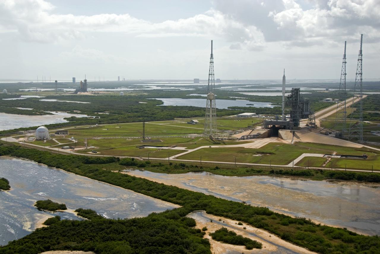 CAPE CANAVERAL, Fla. – At NASA's Kennedy Space Center in Florida, the 327-foot-tall Ares I-X rocket awaits liftoff on Launch Pad 39B on its upcoming flight test. In the distance are space shuttle Atlantis on Kennedy's Launch Pad 39A, and the pads and processing facilities on Cape Canaveral Air Force Station. This is the first time since the Apollo Program's Saturn rockets were retired that a vehicle other than the space shuttle has occupied the pad. Modifications to the pad to support the Ares I-X included the removal of shuttle unique subsystems, such as the orbiter access arm and a section of the gaseous oxygen vent arm, and the installation of three 600-foot lightning towers, access platforms, environmental control systems and a vehicle stabilization system. Part of the Constellation Program, the Ares I-X is the test vehicle for the Ares I. The Ares I-X flight test is set for Oct. 27. For information on the Ares I-X vehicle and flight test, visit http://www.nasa.gov/aresIX. Photo credit: NASA/Kim Shiflett