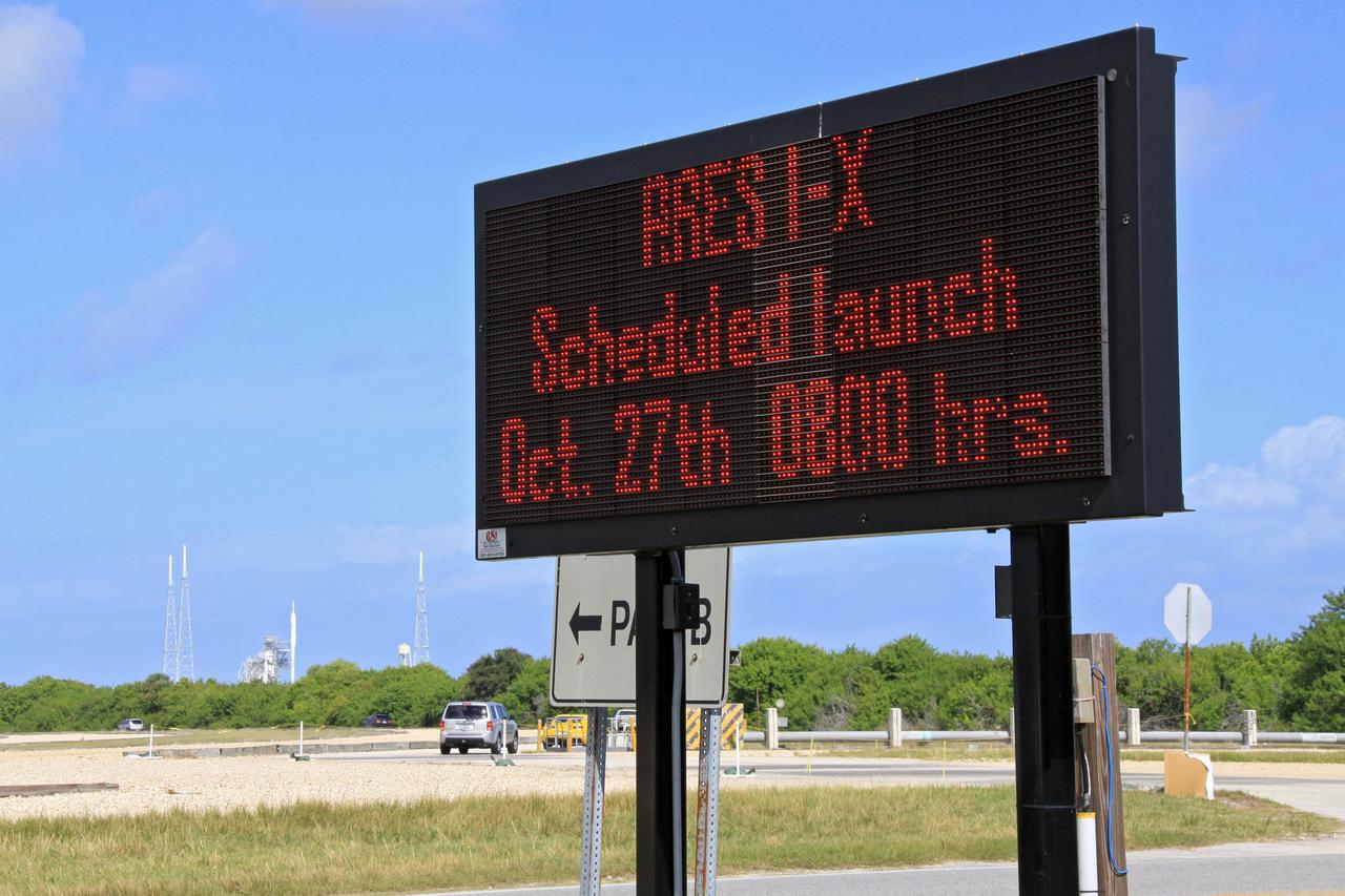 CAPE CANAVERAL, Fla. – A digital sign at the fork in the crawlerway at NASA's Kennedy Space Center in Florida reminds employees that the flight test of the 327-foot-tall Ares I-X rocket, poised for liftoff on Launch Pad 39B in the background, is approaching. This is the first time since the Apollo Program's Saturn rockets were retired that a vehicle other than the space shuttle has resided on the pad. The transfer of the pad from the Space Shuttle Program to the Constellation Program took place May 31. Pad modifications to support the Ares I-X include the removal of shuttle unique subsystems, such as the orbiter access arm and a section of the gaseous oxygen vent arm, and the installation of three 600-foot lightning towers, access platforms, environmental control systems and a vehicle stabilization system. Part of the Constellation Program, the Ares I-X is the test vehicle for the Ares I. The Ares I-X flight test is set for Oct. 27. For information on the Ares I-X vehicle and flight test, visit http://www.nasa.gov/aresIX. Photo credit: NASA/Jack Pfaller