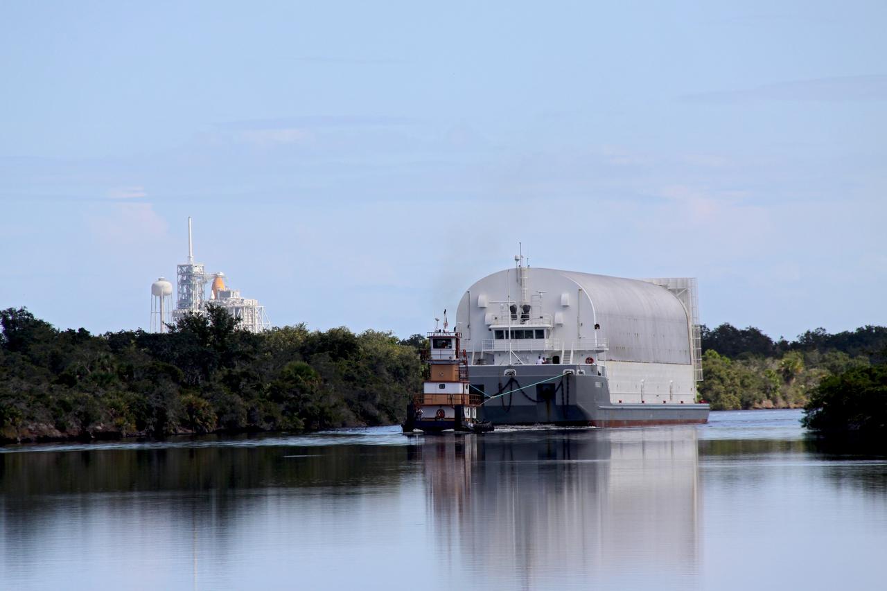 CAPE CANAVERAL, Fla. – A tugboat moves the Pegasus barge, carrying external tank 134, through the Banana River toward the turn basin near the Vehicle Assembly Building, or VAB, at NASA's Kennedy Space Center in Florida. Space Shuttle Atlantis awaits launch on Launch Pad 39A in the background. Pegasus arrived in Florida after an ocean voyage towed by a solid rocket booster retrieval ship from NASA's Michoud Assembly Facility near New Orleans. After Pegasus docks in the turn basin, the fuel tank will be offloaded and transported into the VAB. ET-134 will be used to launch space shuttle Endeavour on the STS-130 mission to the International Space Station. Launch is targeted for Feb. 4, 2010. For information on the components of the space shuttle and the STS-130 mission, visit http://www.nasa.gov/shuttle. Photo credit: NASA/Jack Pfaller
