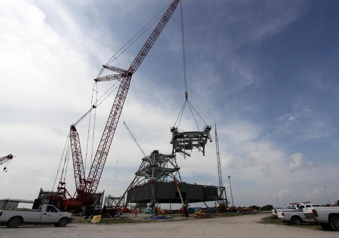 CAPE CANAVERAL, Fla. – At NASA's Kennedy Space Center in Florida, progress continues on the construction of a new mobile launcher, or ML, for the Constellation Program as a crane lifts the third section of the launcher's tower above the platform.    Installation of the first section was on Sept. 24, and the second, on Oct. 15. The tower will have multiple platforms for personnel access and be approximately 345 feet tall. The launcher is being built at the mobile launcher park site area located north of Kennedy's Vehicle Assembly Building to support the Ares I rocket. The ML will provide a base to launch the Ares I, designed to transport the Orion crew exploration vehicle, its crew and cargo to low Earth orbit. The base is being made lighter than space shuttle mobile launcher platforms so the crawler-transporter can pick up the heavier load of the tower and taller rocket.  For information on the Ares I, visit http://www.nasa.gov/ares. Photo credit: NASA/Jack Pfaller
