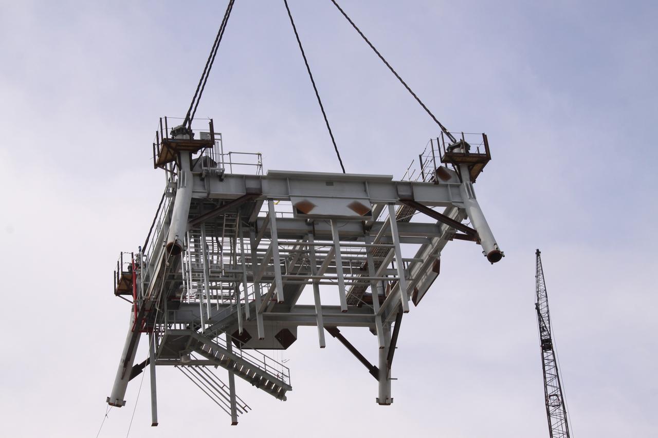 CAPE CANAVERAL, Fla. – At NASA's Kennedy Space Center in Florida, the third section of the tower for a new mobile launcher, or ML, for the Constellation Program is suspended by crane above the platform.    Installation of the first section was on Sept. 24, and the second, on Oct. 15. The tower will have multiple platforms for personnel access and be approximately 345 feet tall. The launcher is being built at the mobile launcher park site area located north of Kennedy's Vehicle Assembly Building to support the Ares I rocket. The ML will provide a base to launch the Ares I, designed to transport the Orion crew exploration vehicle, its crew and cargo to low Earth orbit. The base is being made lighter than space shuttle mobile launcher platforms so the crawler-transporter can pick up the heavier load of the tower and taller rocket.  For information on the Ares I, visit http://www.nasa.gov/ares. Photo credit: NASA/Jack Pfaller
